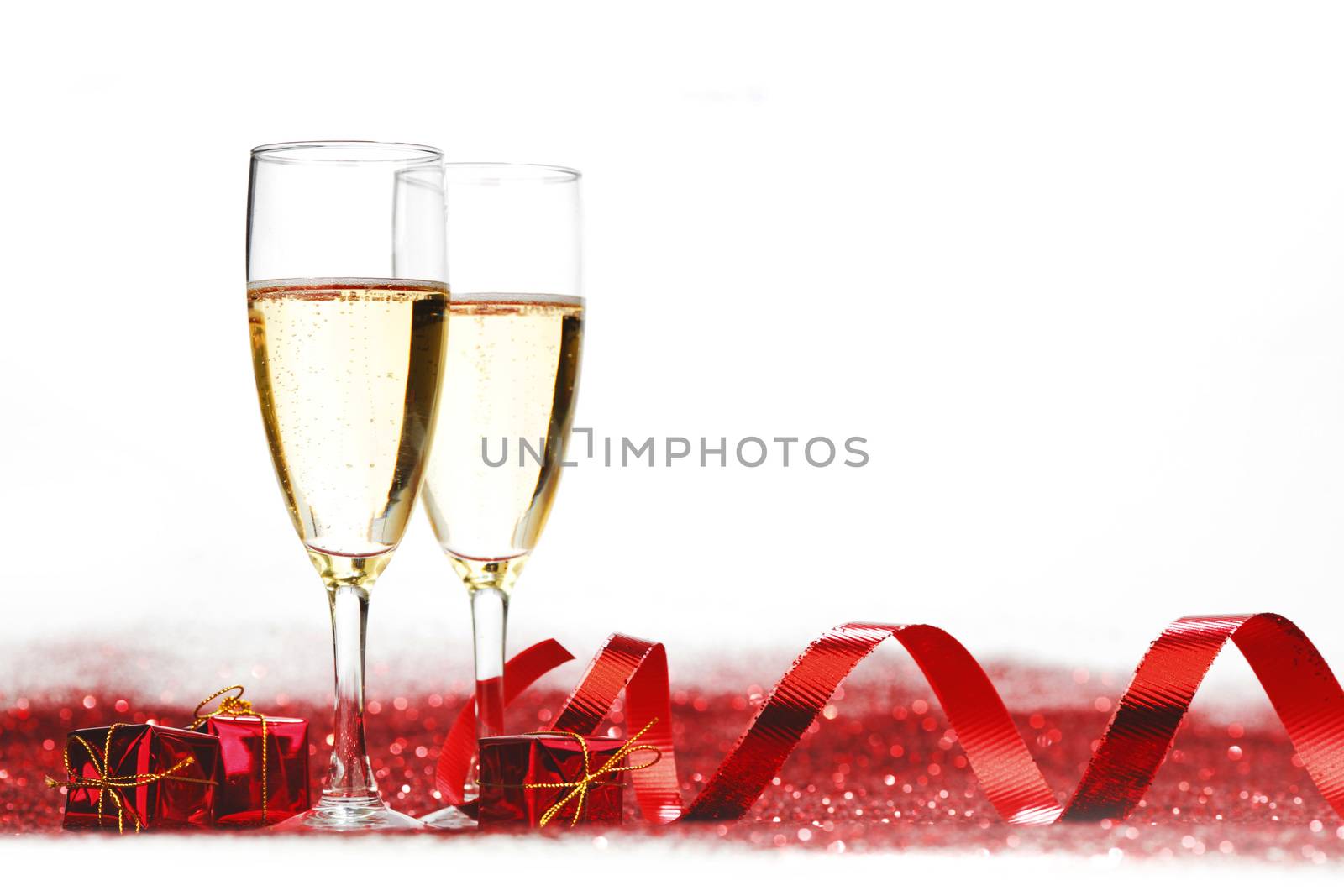 Glasses with Champagne and gifts on red glitters isolated on white background