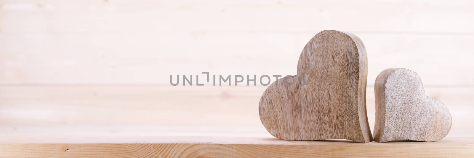 Two handmade wooden carved hearts on light wood background couple relationship Valentine day concept