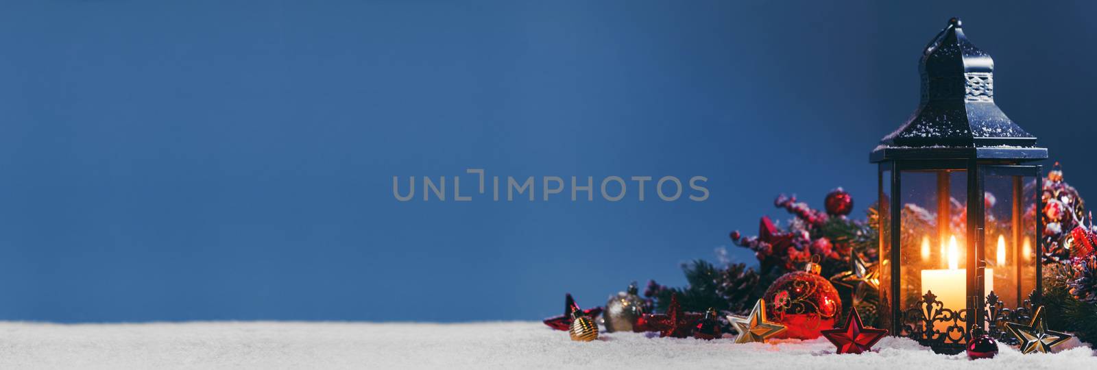 Christmas composition of lantern colorful ornaments balls stars candles and fir tree branches on snow