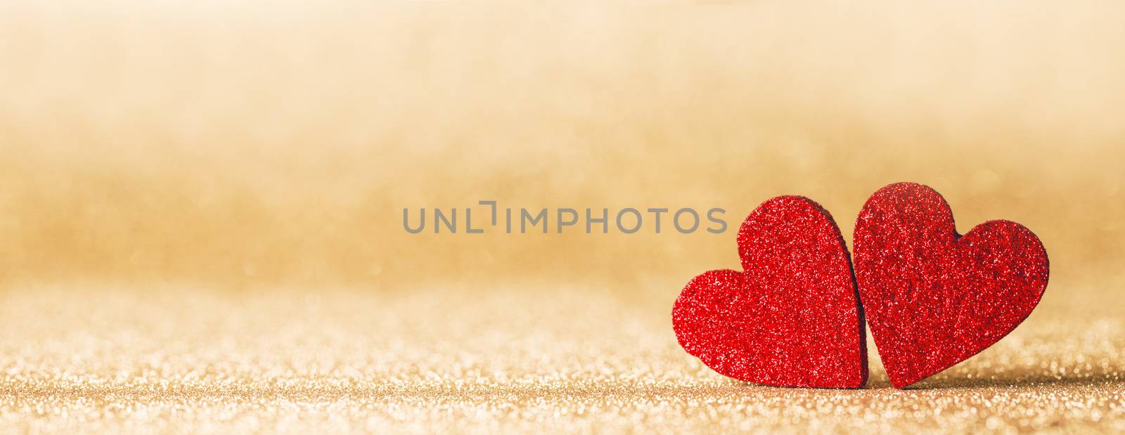 Two small handmade red glitter hearts on bright golden lights bokeh background Valentines day card