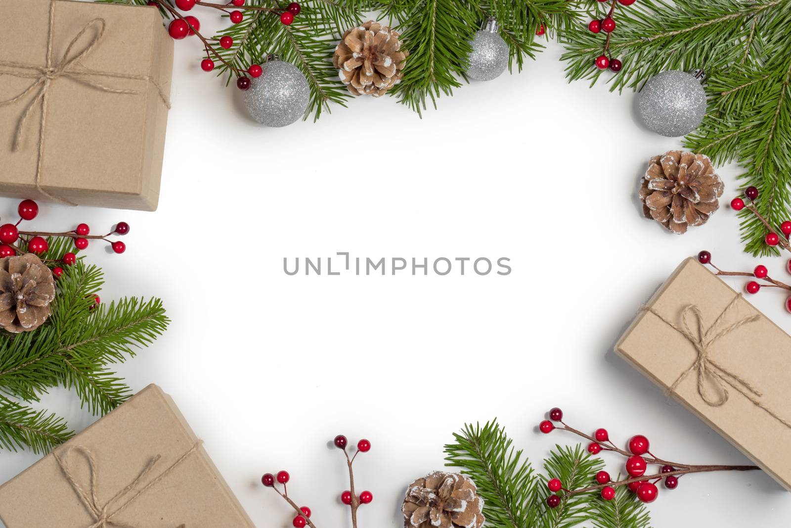 Christmas tree branch with snow , pine cones, red berries and gift boxes on white background with copy space