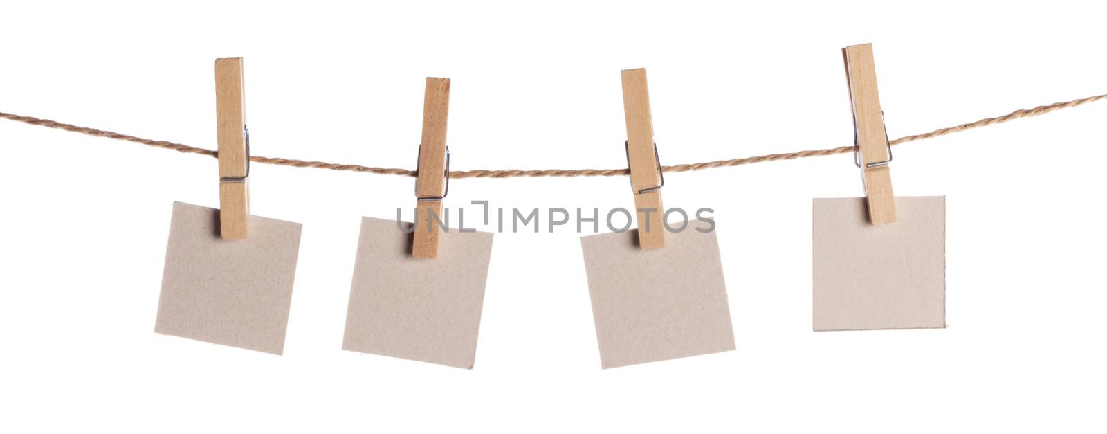 Set of four blank paper notes held on a string with clothespins isolated on white background