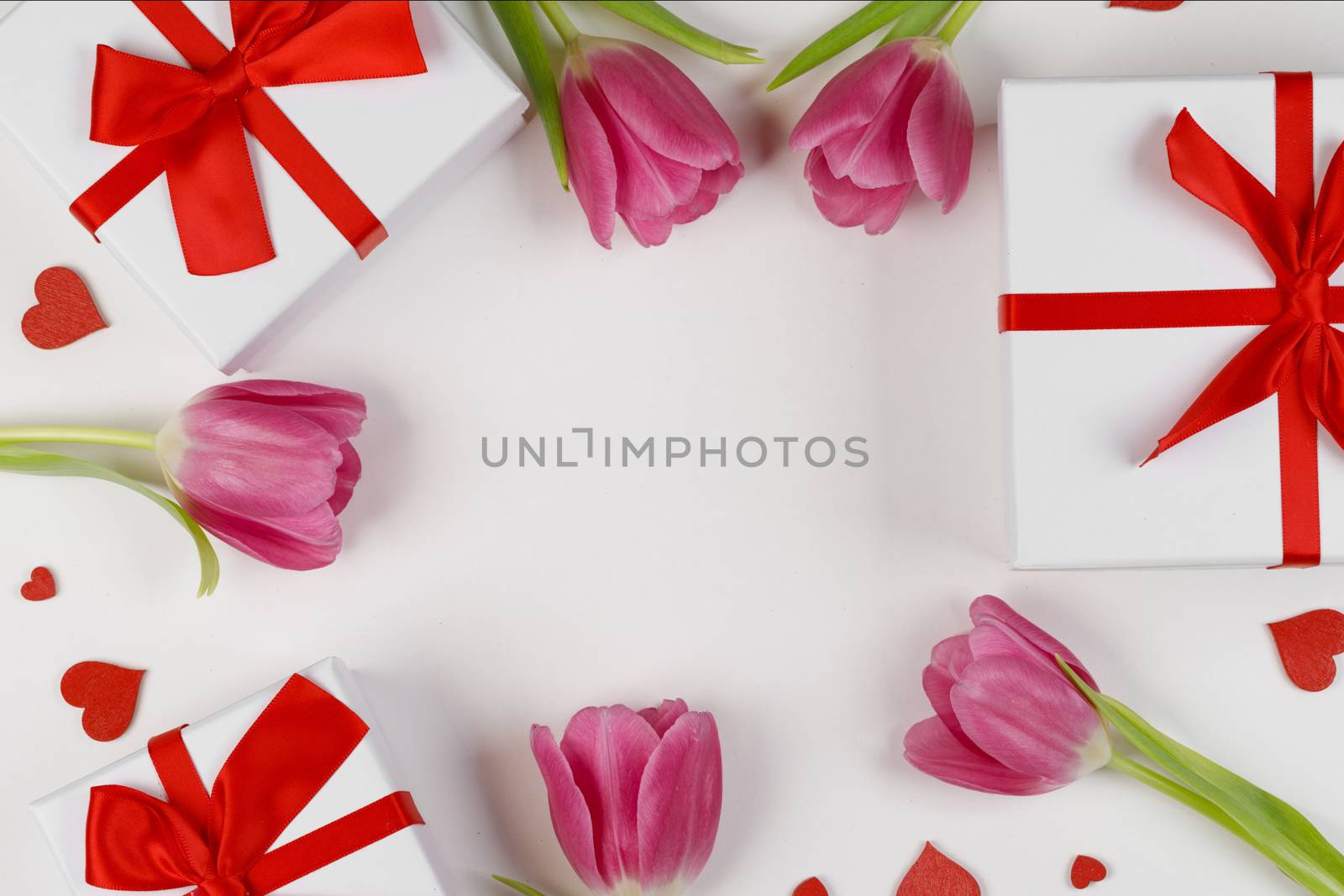 Pink tulip flowers gifts and red hearts composition on white background top view with copy space. Valentine's day, birthday, wedding, Mother's day concept. Copy space