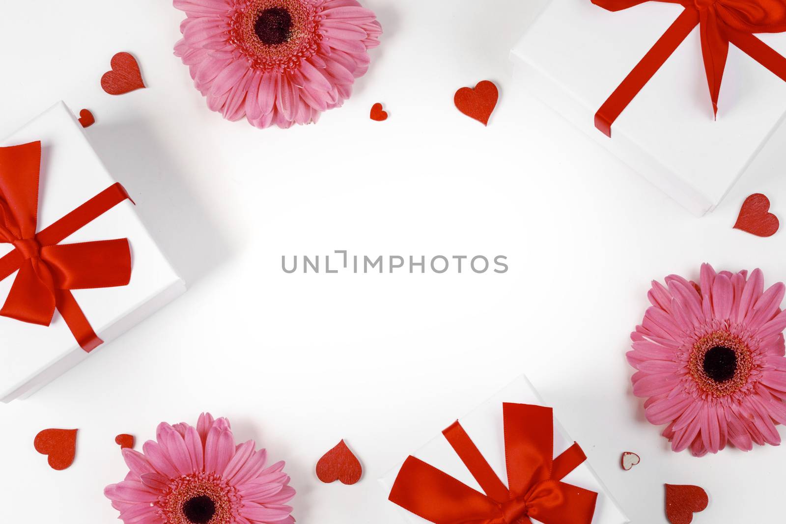 Pink gerbera flowers gifts and red hearts composition on white background top view with copy space. Valentine's day, birthday, wedding, Mother's day concept. Copy space