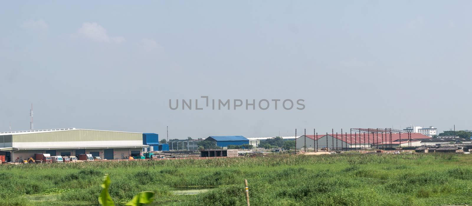 Industrial site power plant landscape. Industry surrounded by rural agricultural field and green summer meadow. A beautiful non-urban scenic environment of Rural Countryside of India, south asia pac.