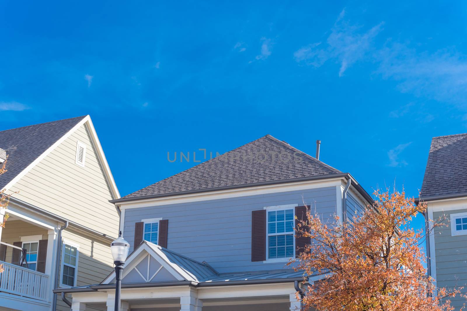 Colorful autumn leaves around cottage style homes in suburbs Dallas, Texas with wood siding, shingle tiles, covered porch. Cladding layer thermal insulation, weather resistance, vintage house