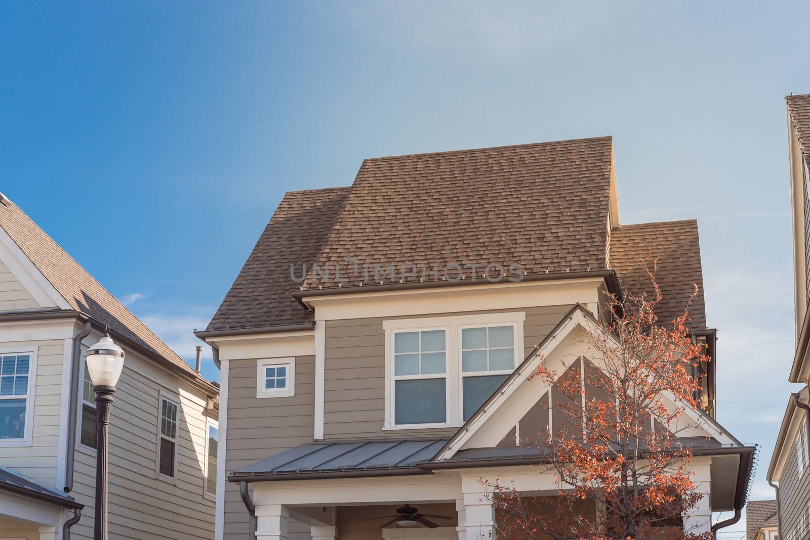 Cottage style homes in suburbs Dallas, Texas with wood siding, shingle tiles, covered porch and fall foliage. Cladding layer thermal insulation, weather resistance, vintage house appearance