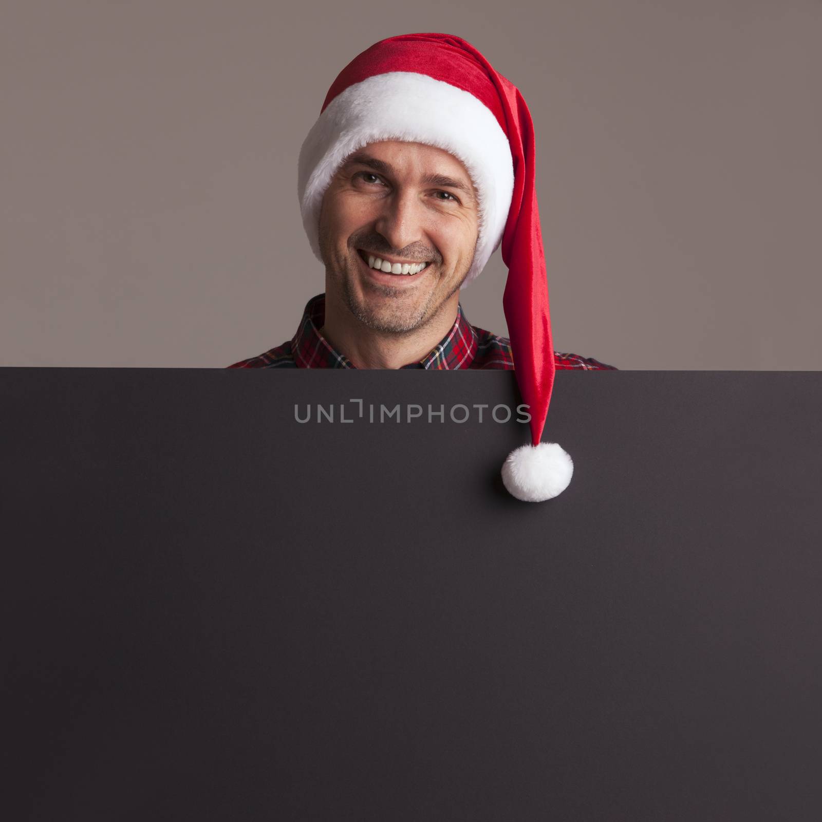 Man in santa christmas hat holding placard by ALotOfPeople