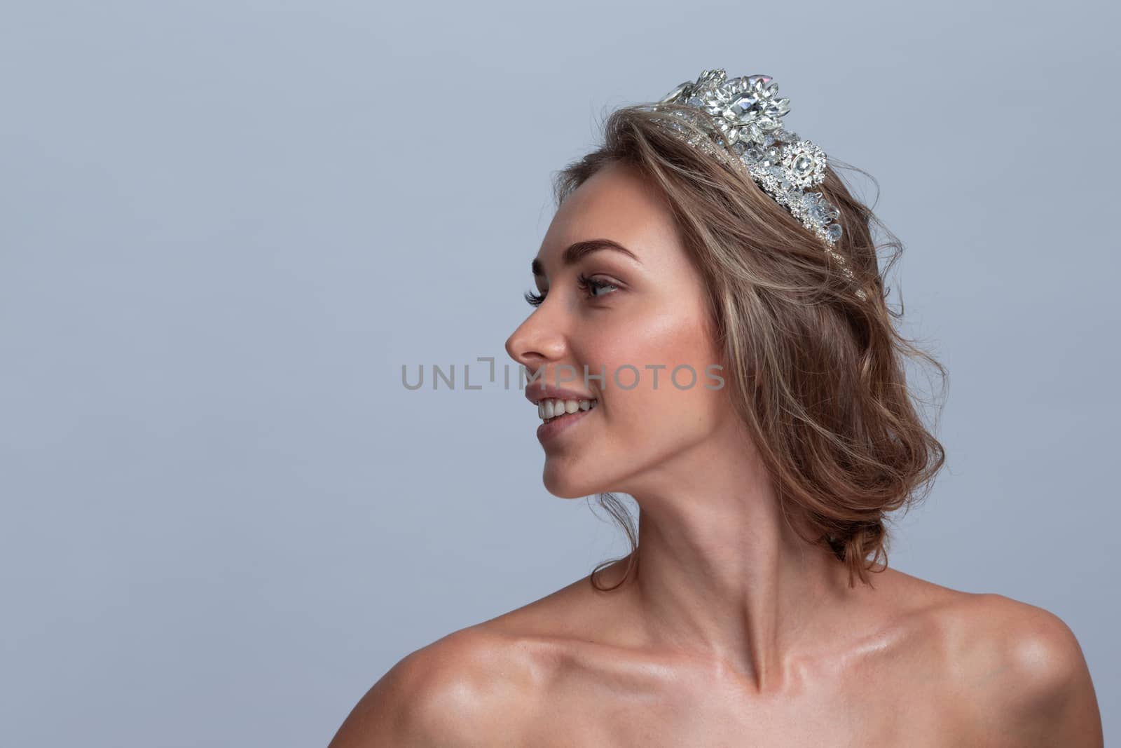 Fashion shot of a beautiful young woman with diadem on gray background