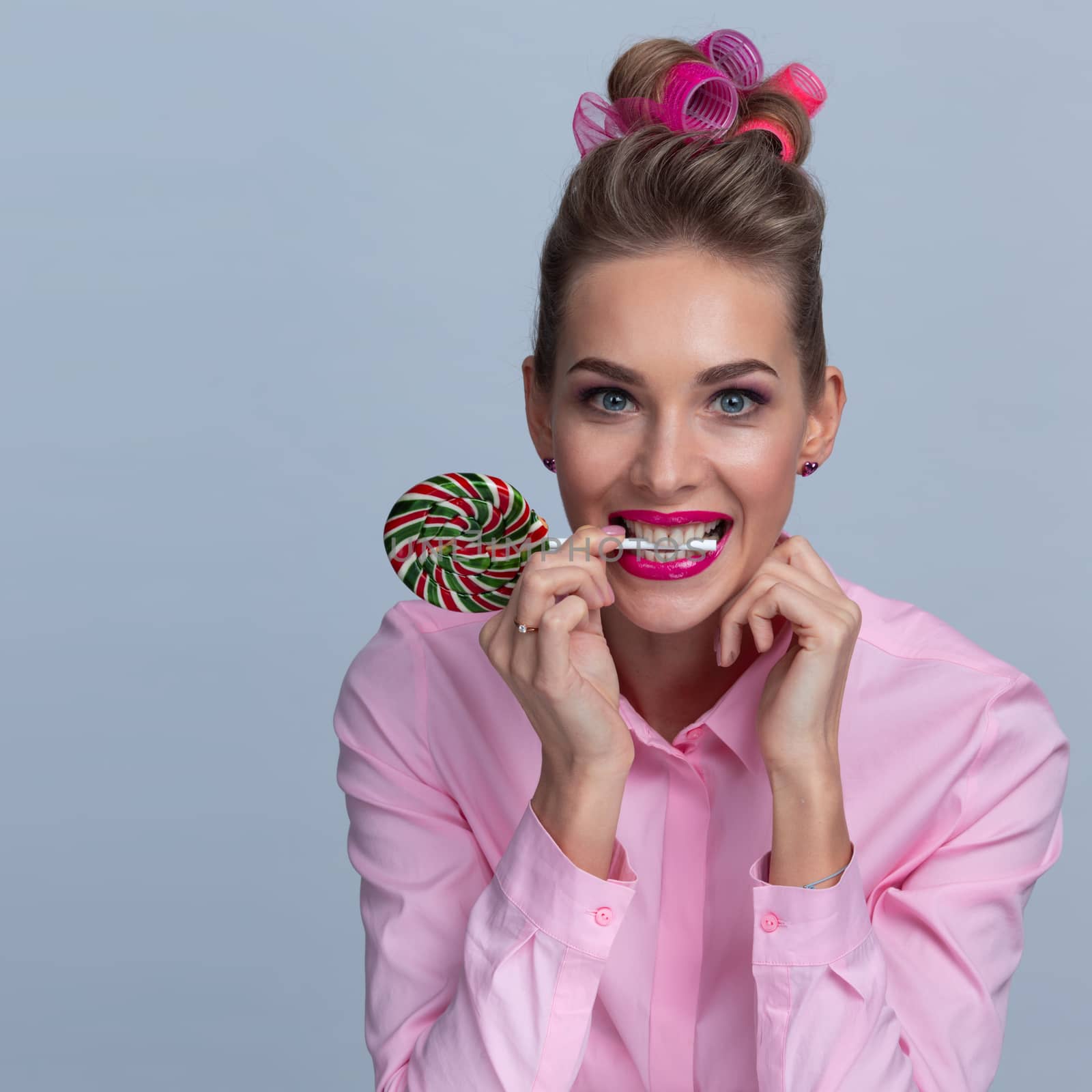 Pretty woman in hair curlers getting ready for Christmas New Year party holding big lollipop