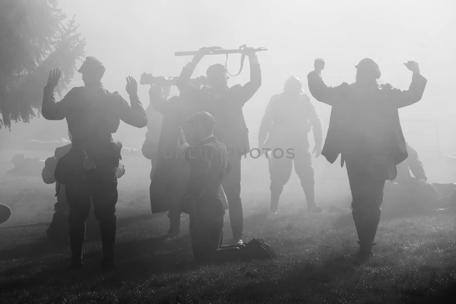 Silhouettes of Soldiers in uniforms during Worl War with rifles on battlefield. All area is in smoke and sunrays peeking thru.