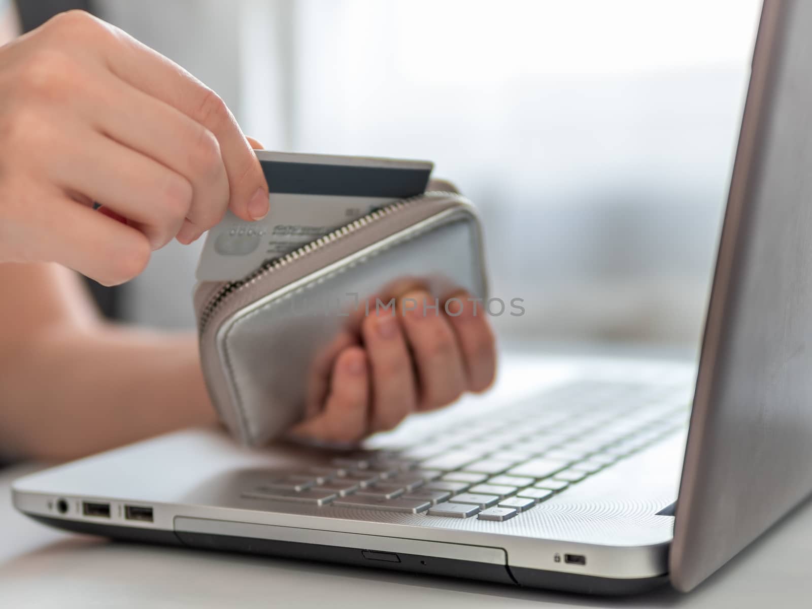 Online shopping concept. Close-up woman's hands get credit card from wallet near laptop for online shopping