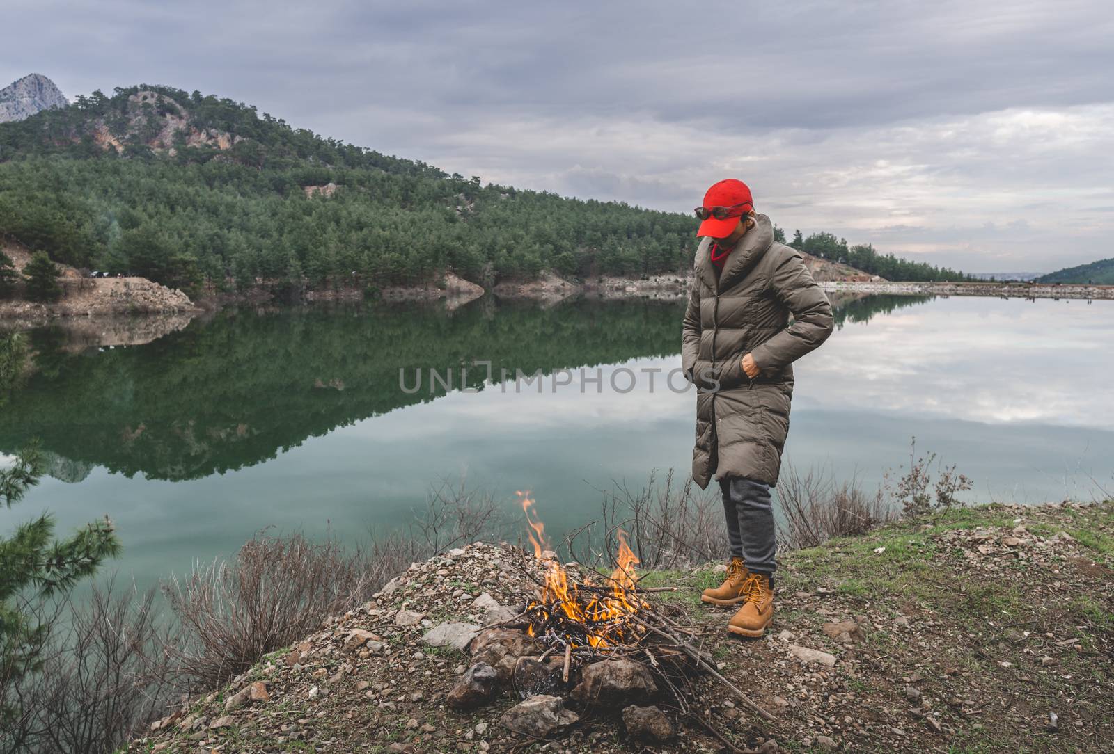 Female wearing coat heats up in cold weather by fire.