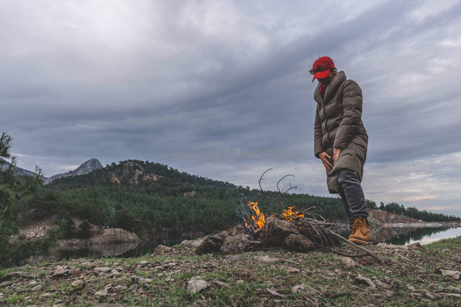 Female wearing coat heats up in cold weather by fire.