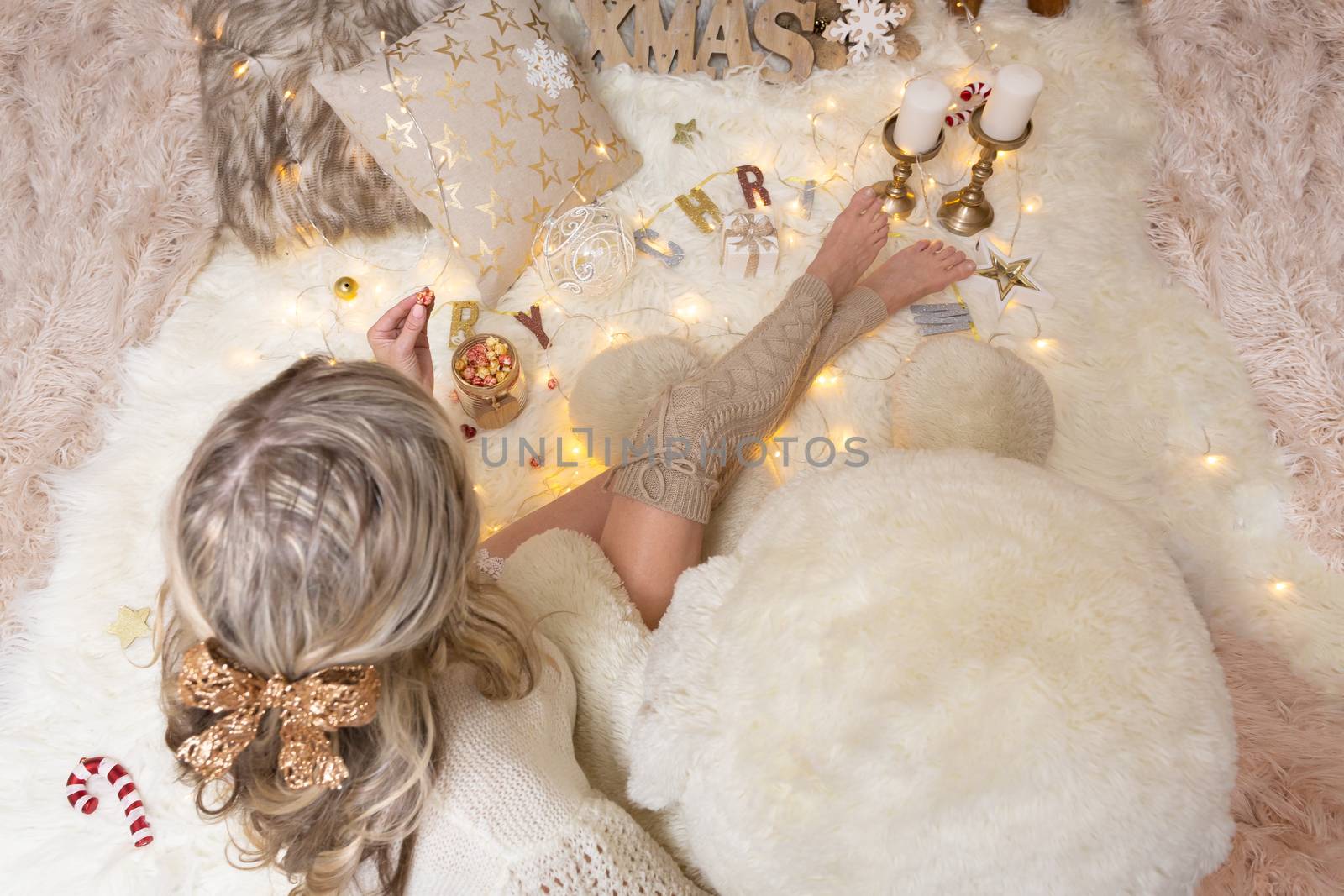 Female sitting on fluffy rugs eating candy cane flavoured popcorn at Christmas time holiday season