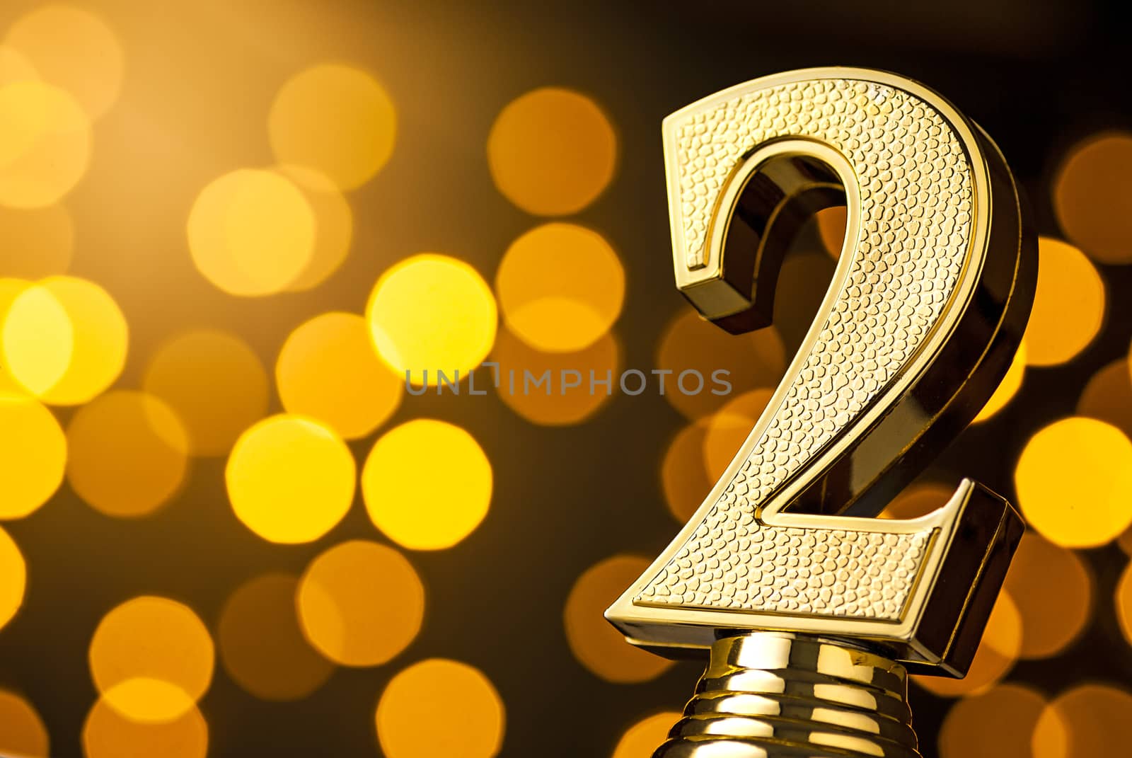 Second placed runner up gold award trophy over a festive background of golden bokeh effect party lights