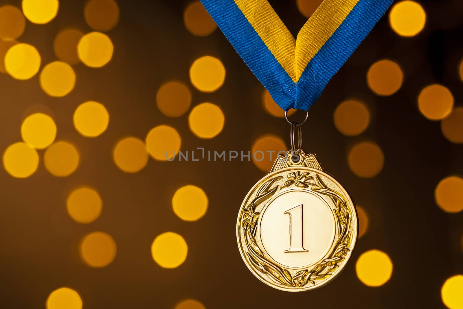 Gold champion or winners medallion on a ribbon over a colorful background with festive golden bokeh of party lights to celebrate the win