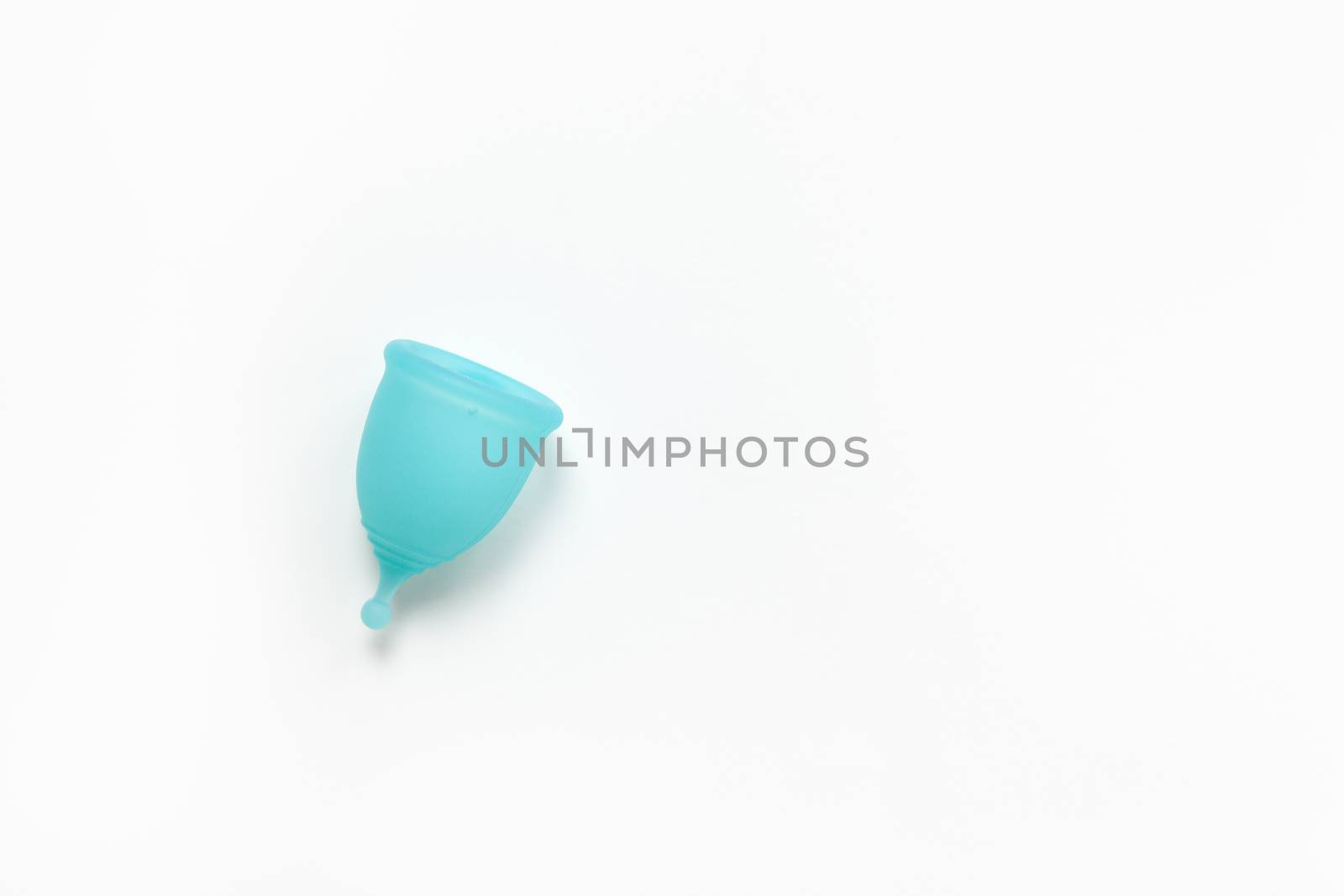 Turquoise menstrual cup on white background. Concept zero waste, savings, minimalism, environmental conservation, sustainable lifestyle. Feminine hygiene product, flatlay, copy space. Horizontal.