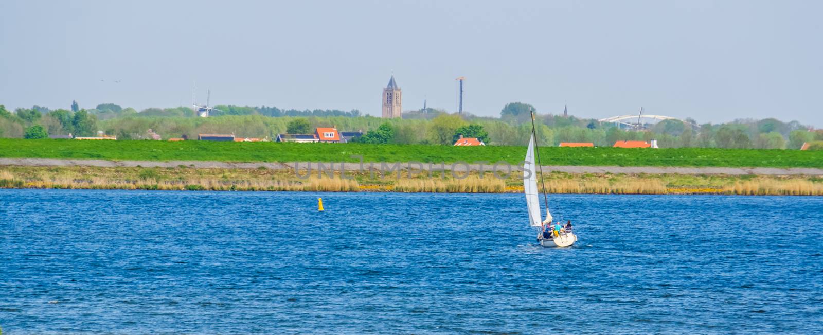 ship sailing on the oosterschelde with the city scenery in the background, Tholen, Zeeland, The netherlands by charlottebleijenberg