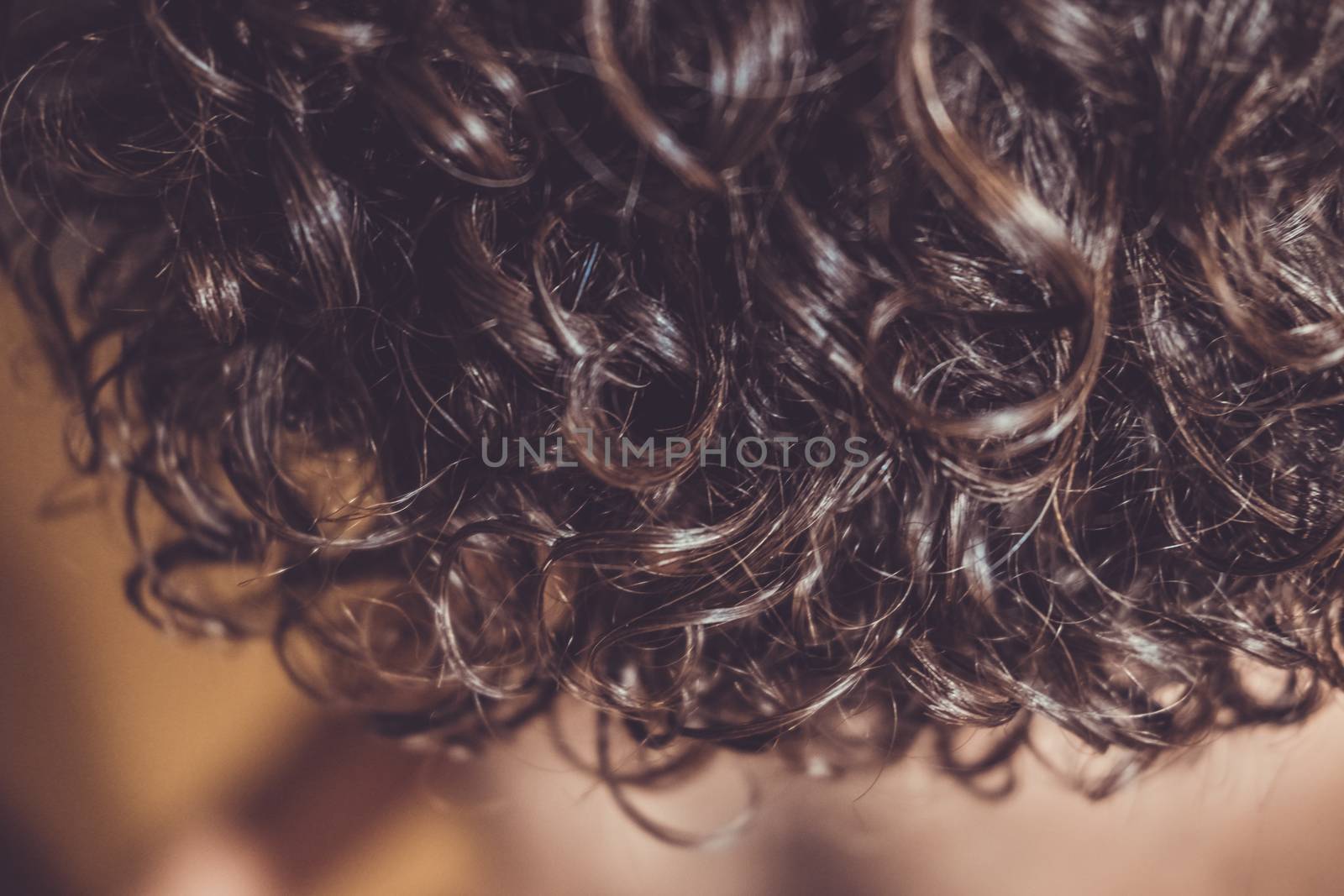 Natural brown curly hair sparkling under flash light