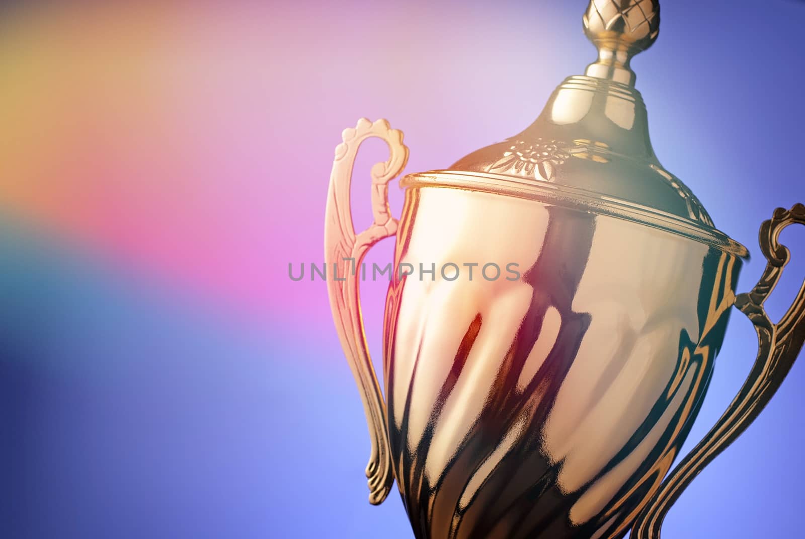 Close up of a silver trophy prize with an ornate lid and handles for the winner of a championship event or competition on blue with copyspace