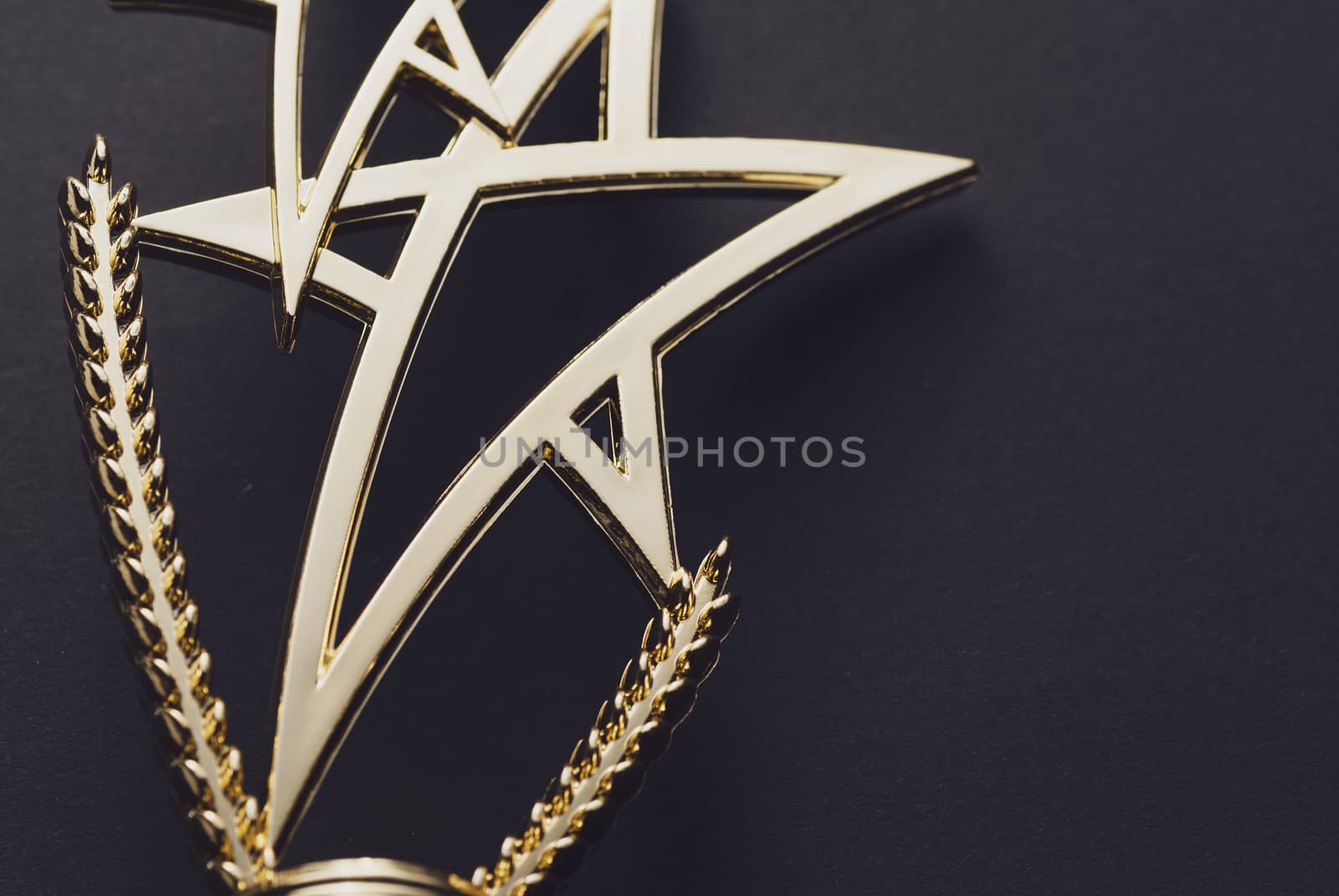 Golden trophy with pedestal in shape of triple star on black background