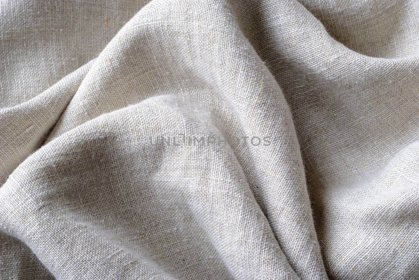 Gathered and folded texture of woven linen fabric with natural fibres in a close up full frame view