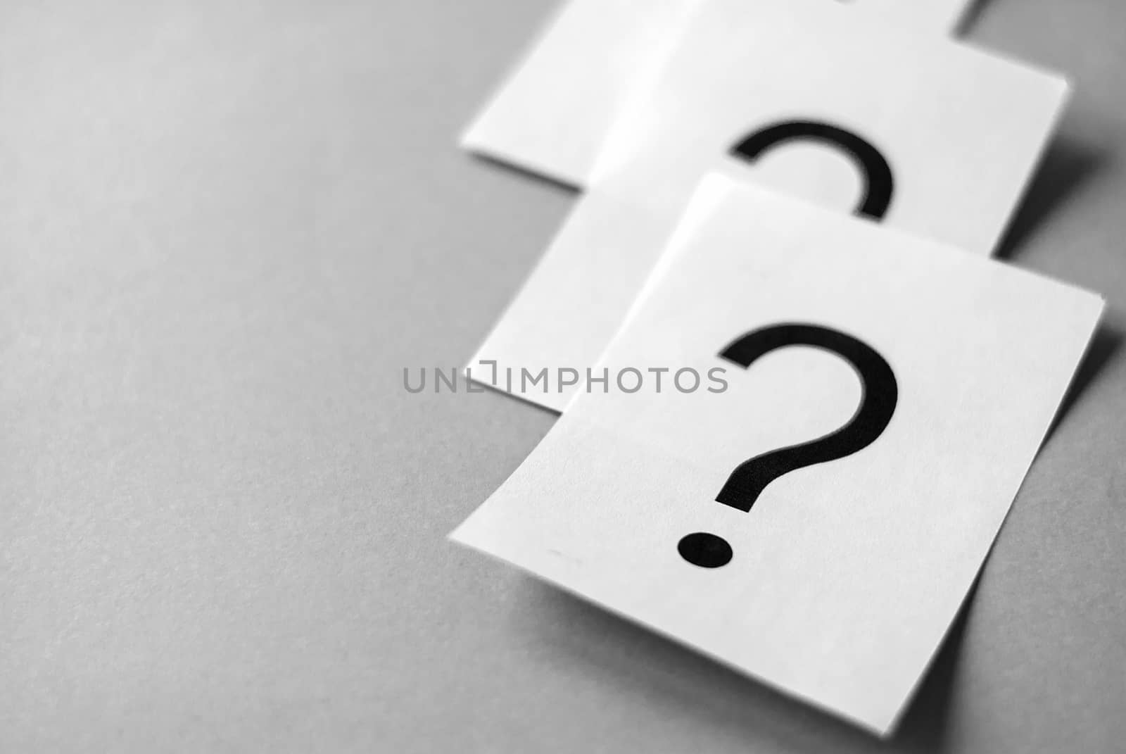 White cards with printed question marks on grey background with copy space. Queue of questions to be answer concept