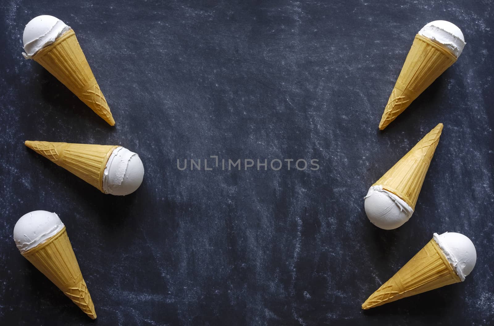 cones with creamy Italian ice cream dessert arranged as a side border on a textured grey background with copy space viewed from overhead