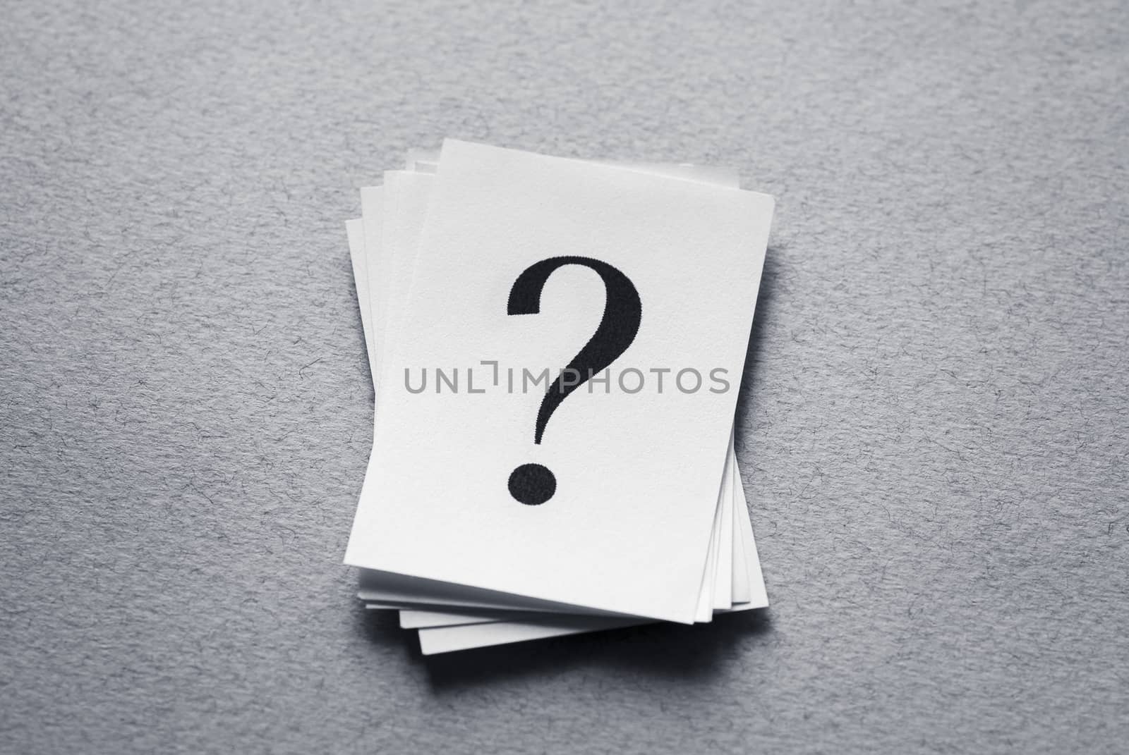 Question mark on paper cards on gray background.