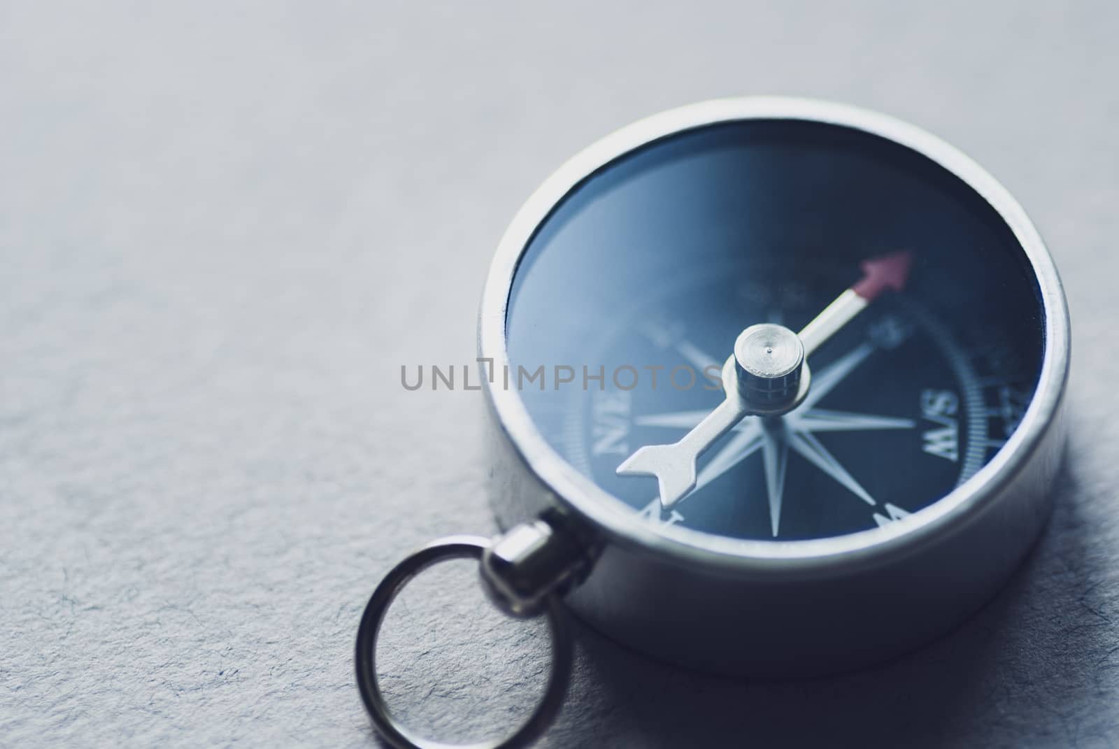 Small magnetic compass for navigation on a grey background with coy space in a conceptual image