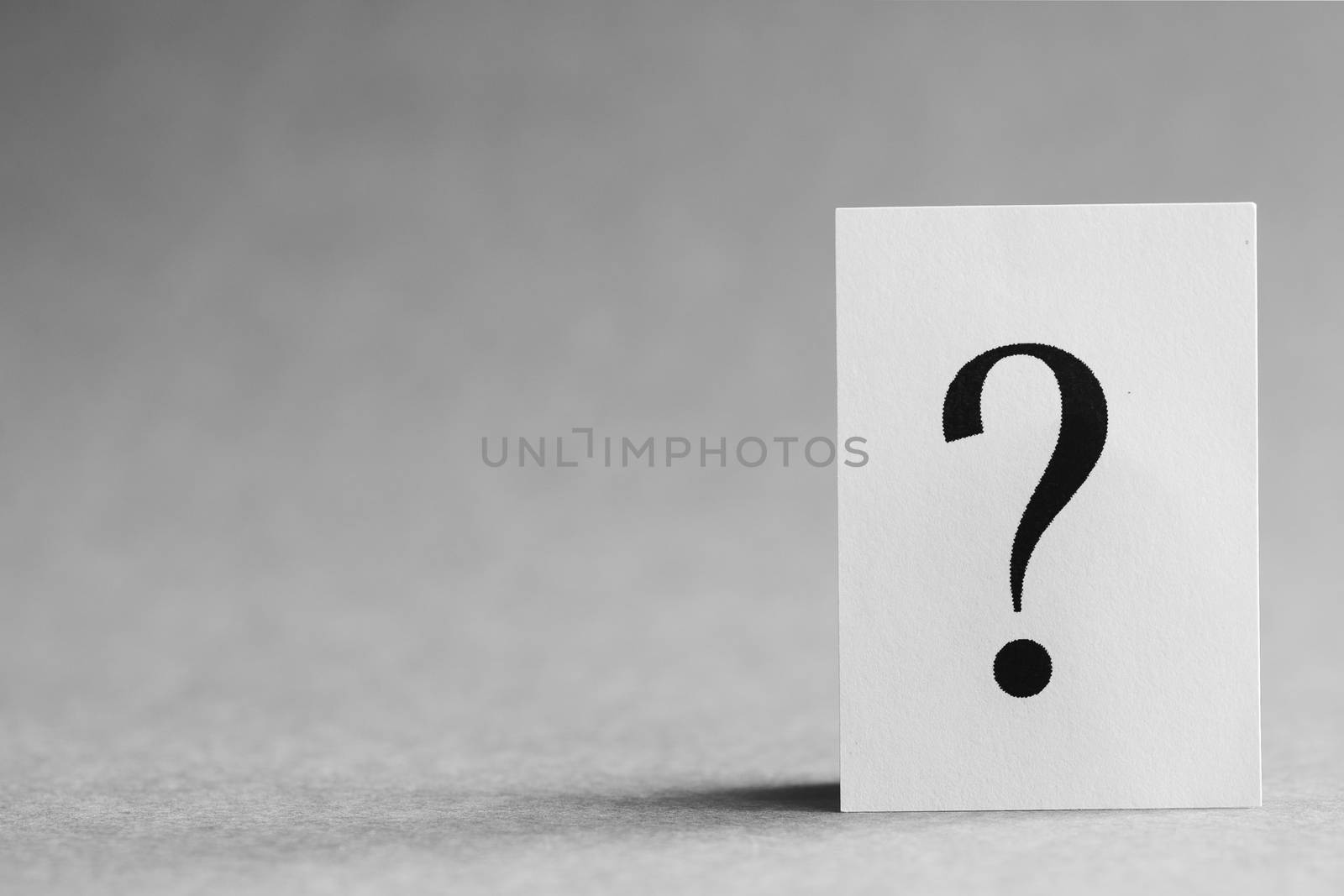 Paper card with a question mark on a gray background, concept.