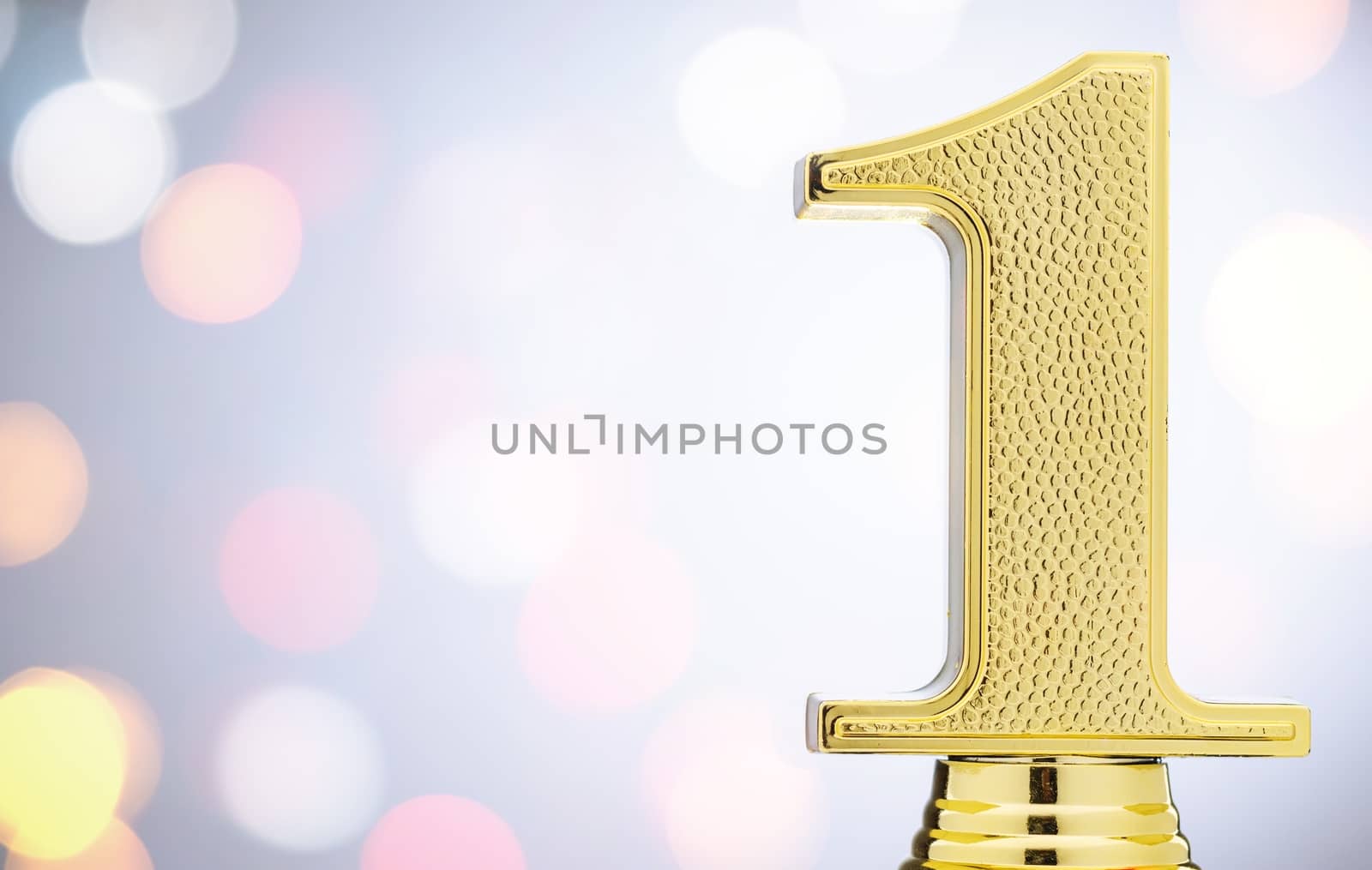 Winners 1st place gold trophy with copy space placed to the side over white for a competition or championship victory or win and bokeh