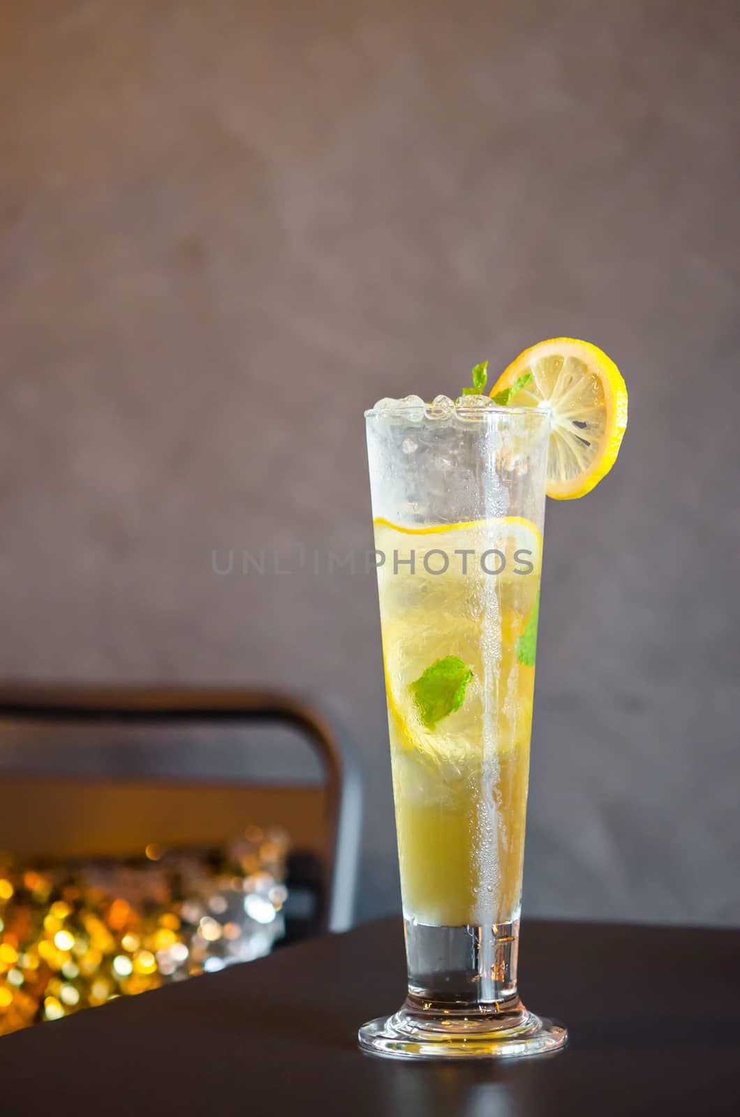 Mojito cocktail with lime and mint in high glass on wooden table.