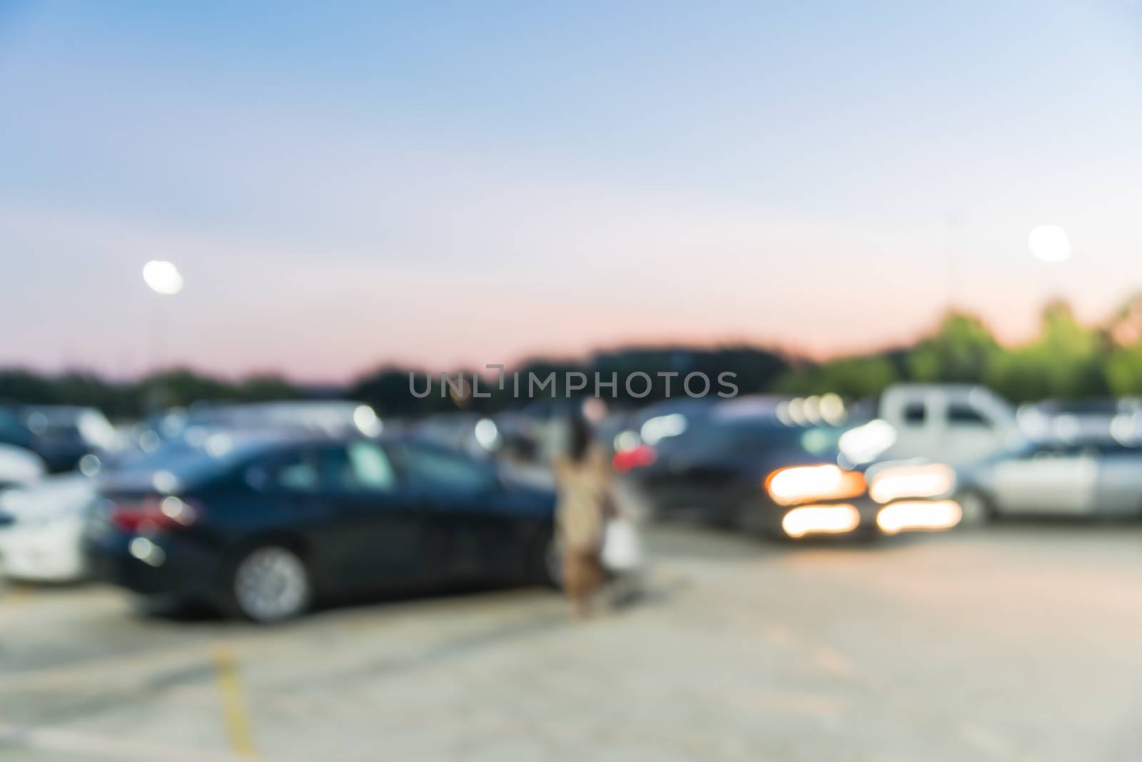 Motion blurred customer out shopping in holidays season at modern shopping center in Humble, Texas, US. Busy outdoor parking lots at sunset, mall complex uncovered parking with light lampposts