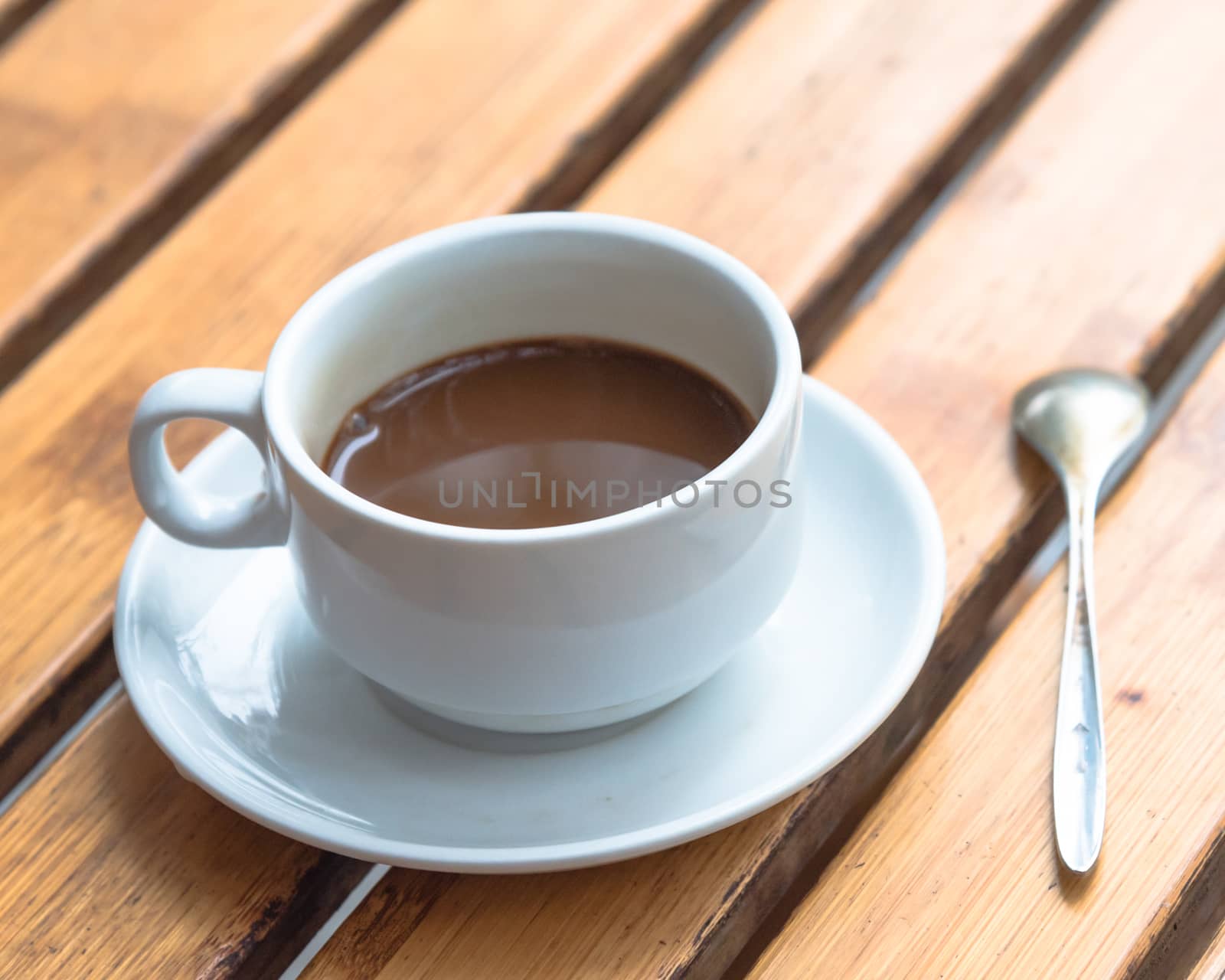 Close-up Vietnamese milk coffee in white ceramic cup with spoon and saucer by trongnguyen