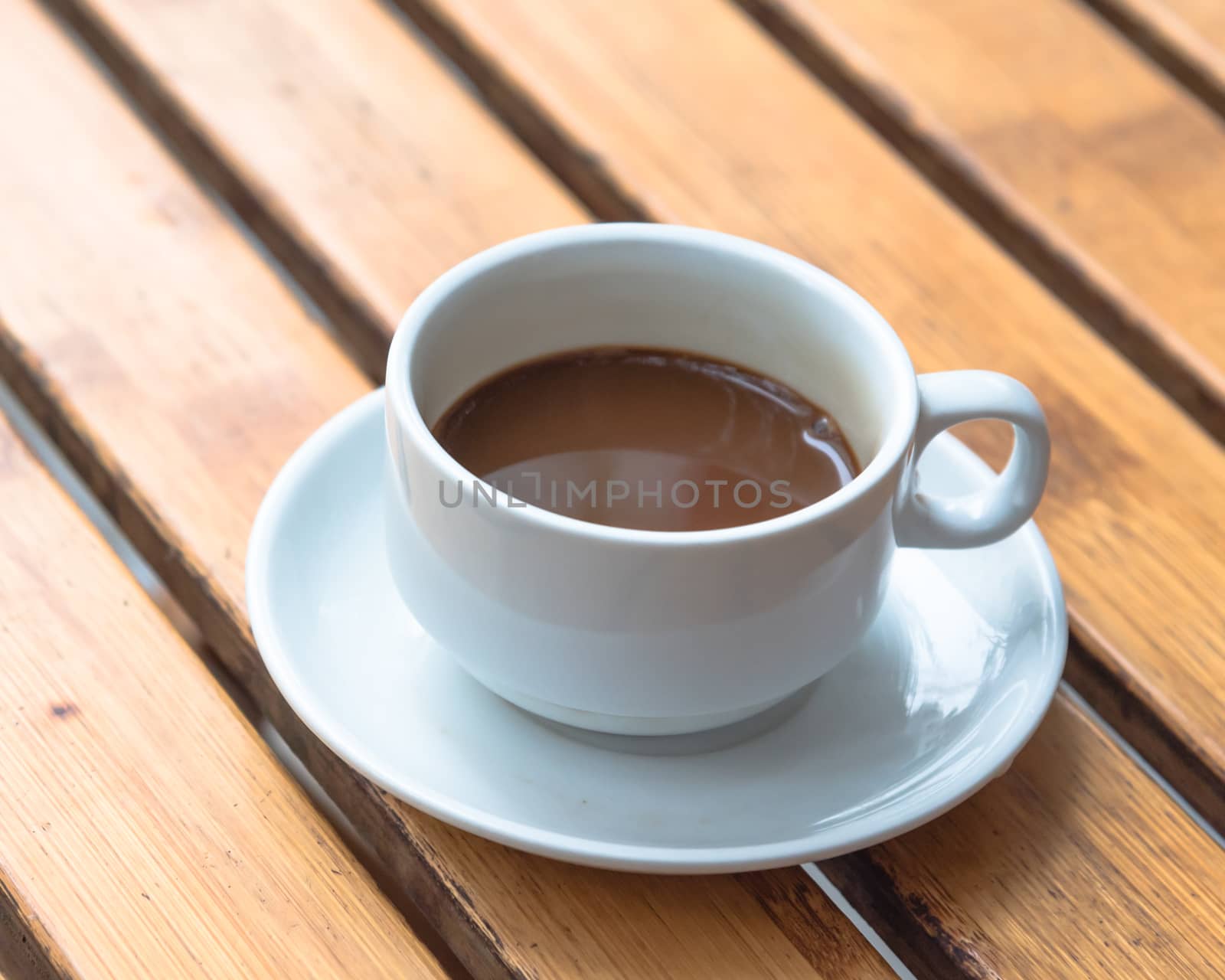 Vietnamese milk coffee in white ceramic cup and saucer on outdoor wooden table. Top view a morning Vietnamese gourmet drink. Food concept.