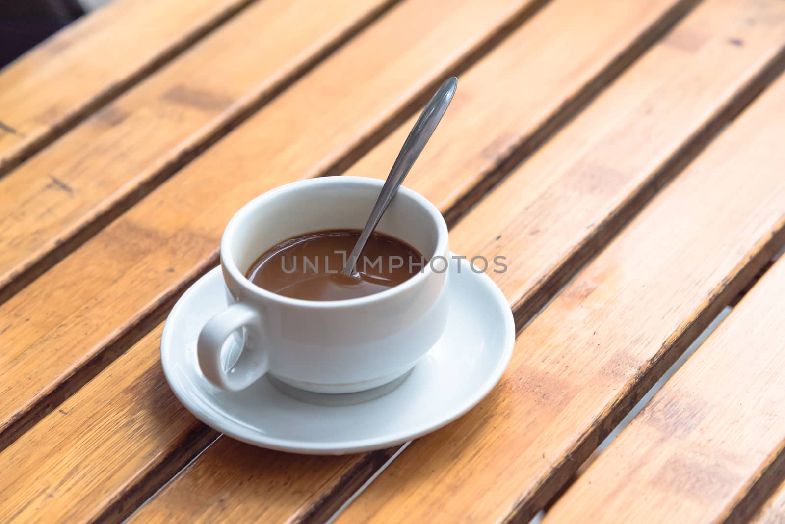 Popular Vietnamese milk coffee in ceramic cup and saucer with stainless spoon on outdoor wooden table. Top view a morning Vietnamese gourmet drink. Food concept.