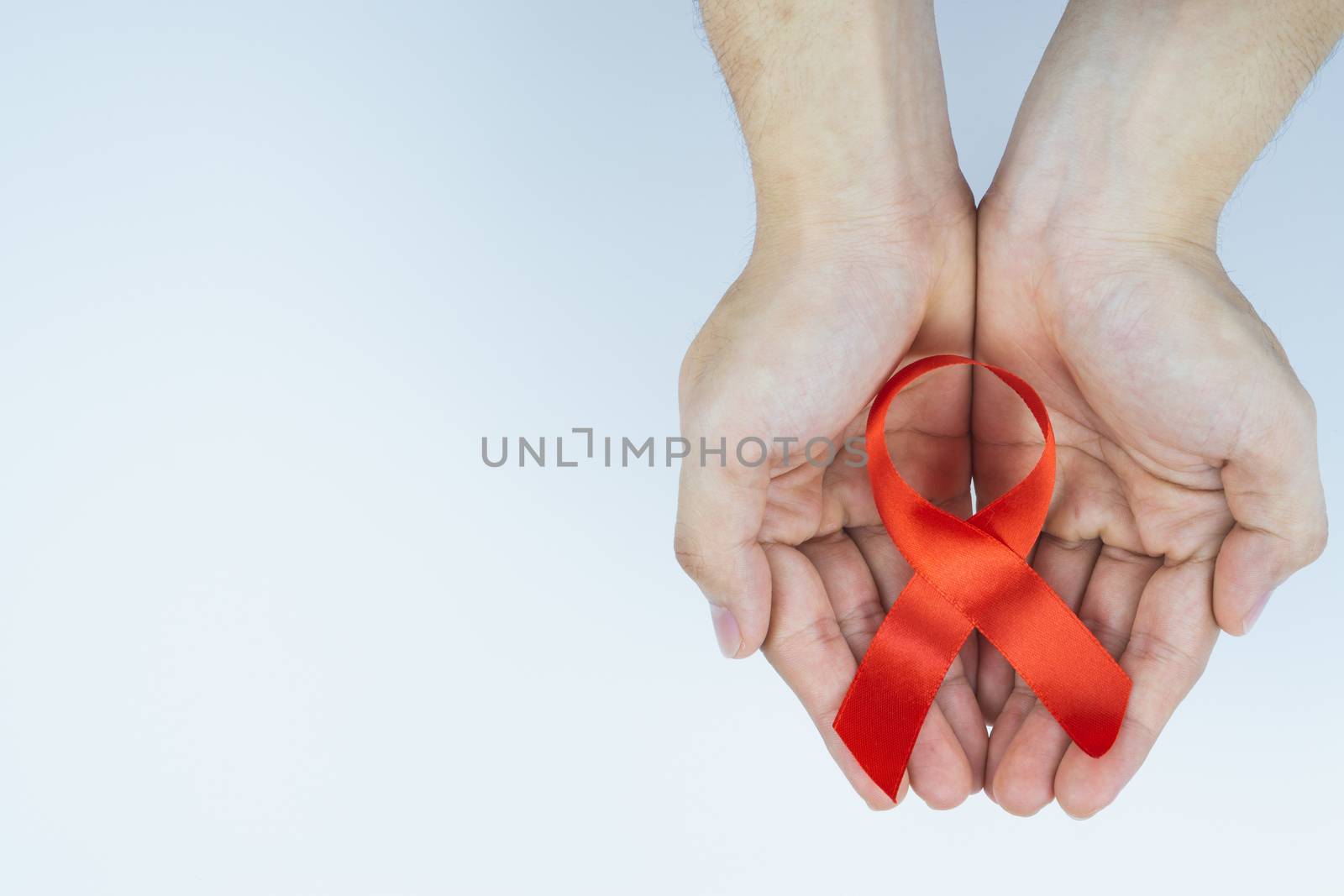 Aids awareness, male hands holding red AIDS awareness ribbon on white background. World Aids Day, Healthcare and medical concept.