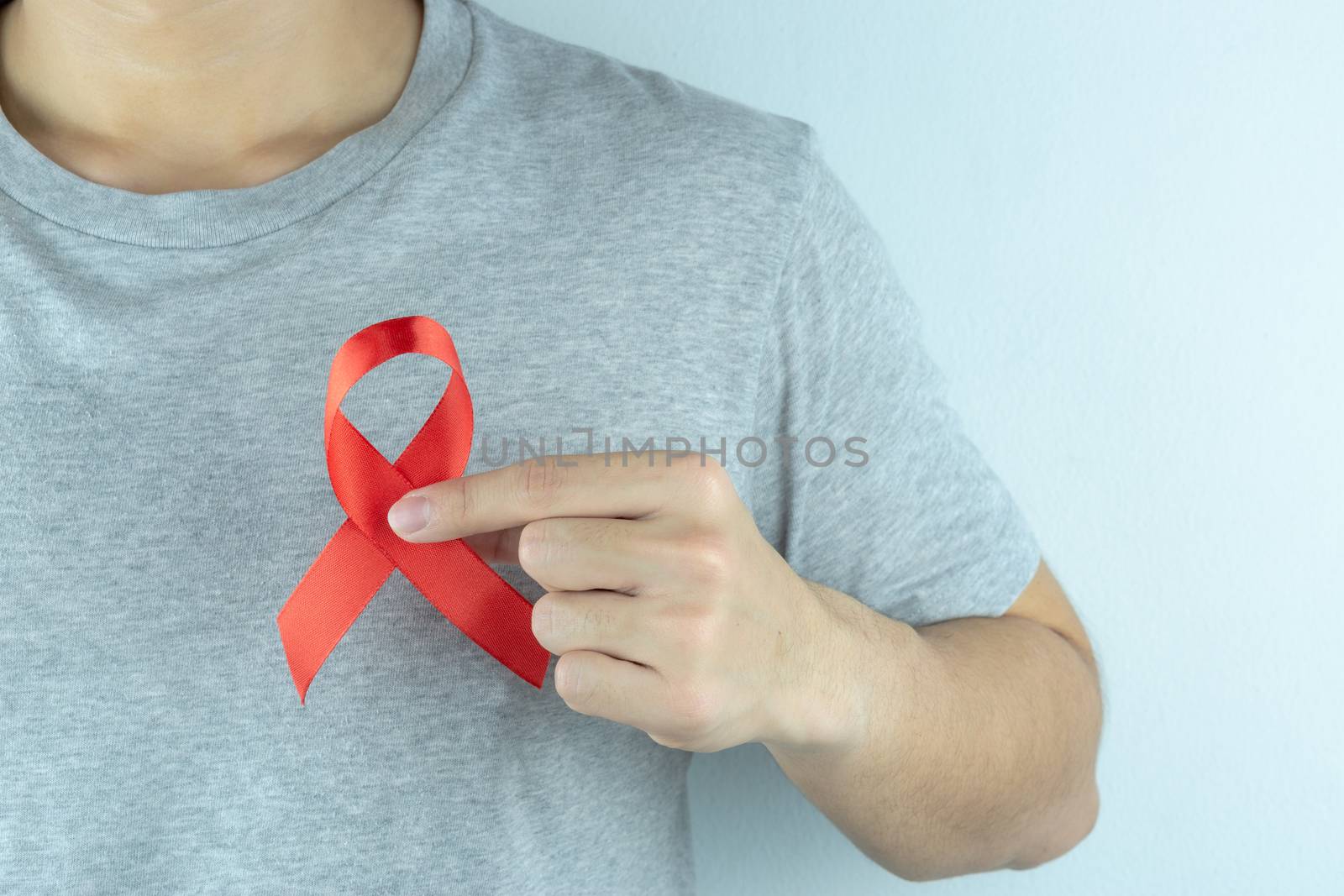 Aids awareness, male hands holding red AIDS awareness ribbon. World Aids Day, Healthcare and medical concept.