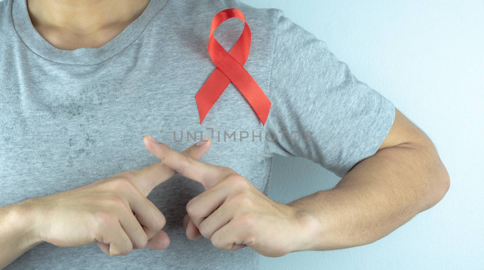 Aids awareness, male hands holding red AIDS awareness ribbon. World Aids Day, Healthcare and medical concept.