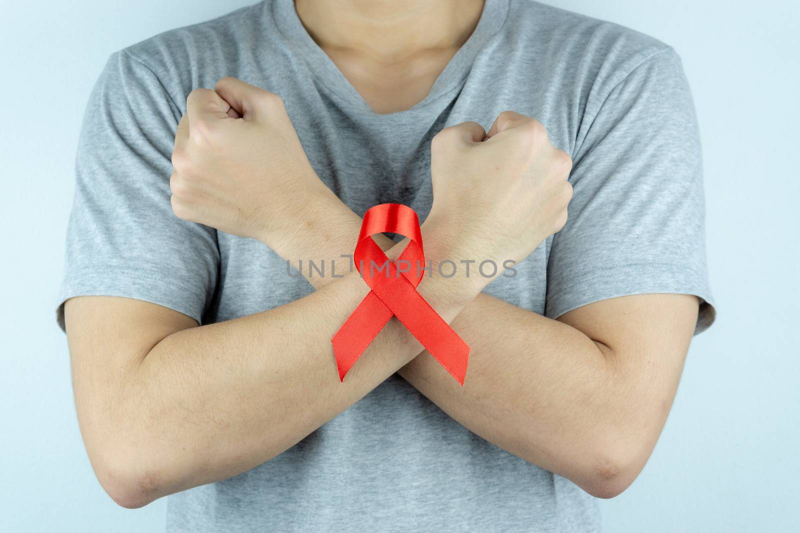 Aids awareness, male hands holding red AIDS awareness ribbon. World Aids Day, Healthcare and medical concept.