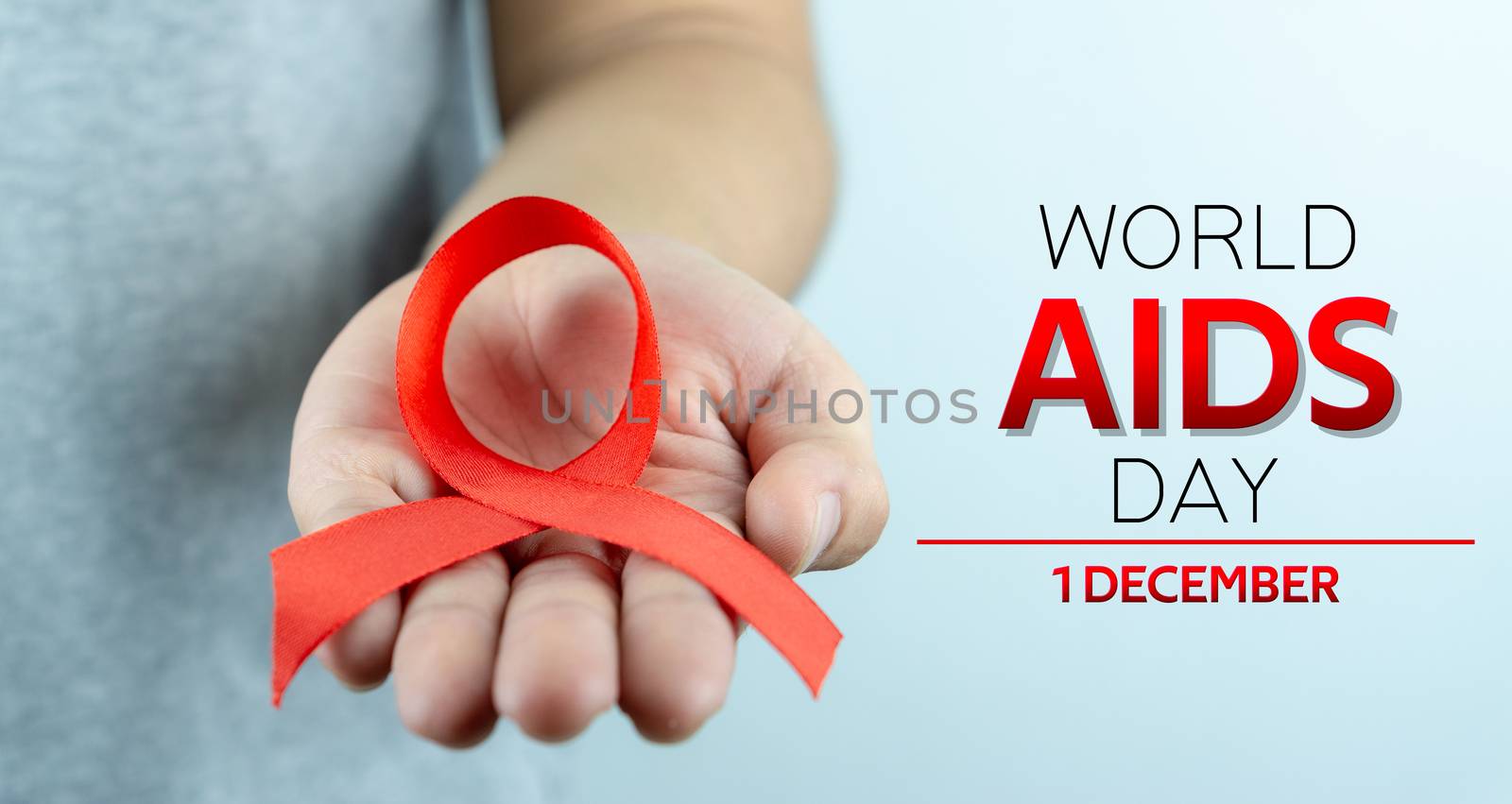 Aids awareness, male hands holding red AIDS awareness ribbon. World Aids Day, Healthcare and medical concept.