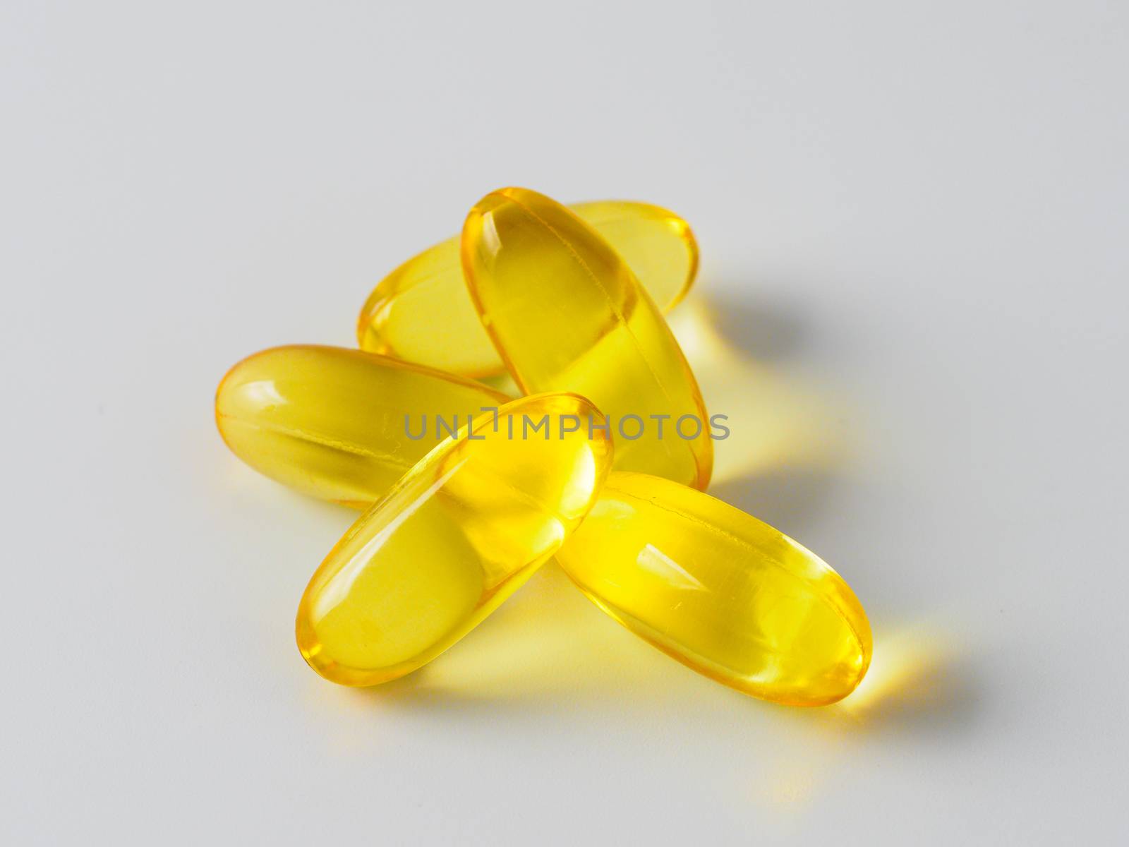 Omega 3 fish oil capsules isolated on white background. Golden color capsules - vitamin E, D or multivitamin.