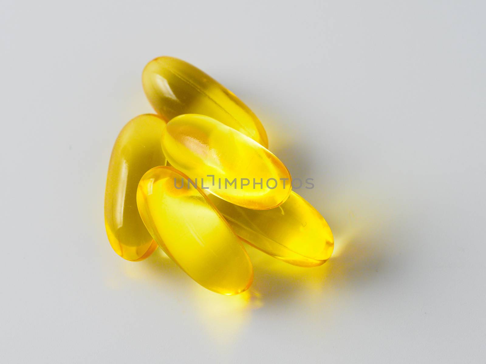 Omega 3 fish oil capsules isolated on white background. Golden color capsules - vitamin E, D or multivitamin.