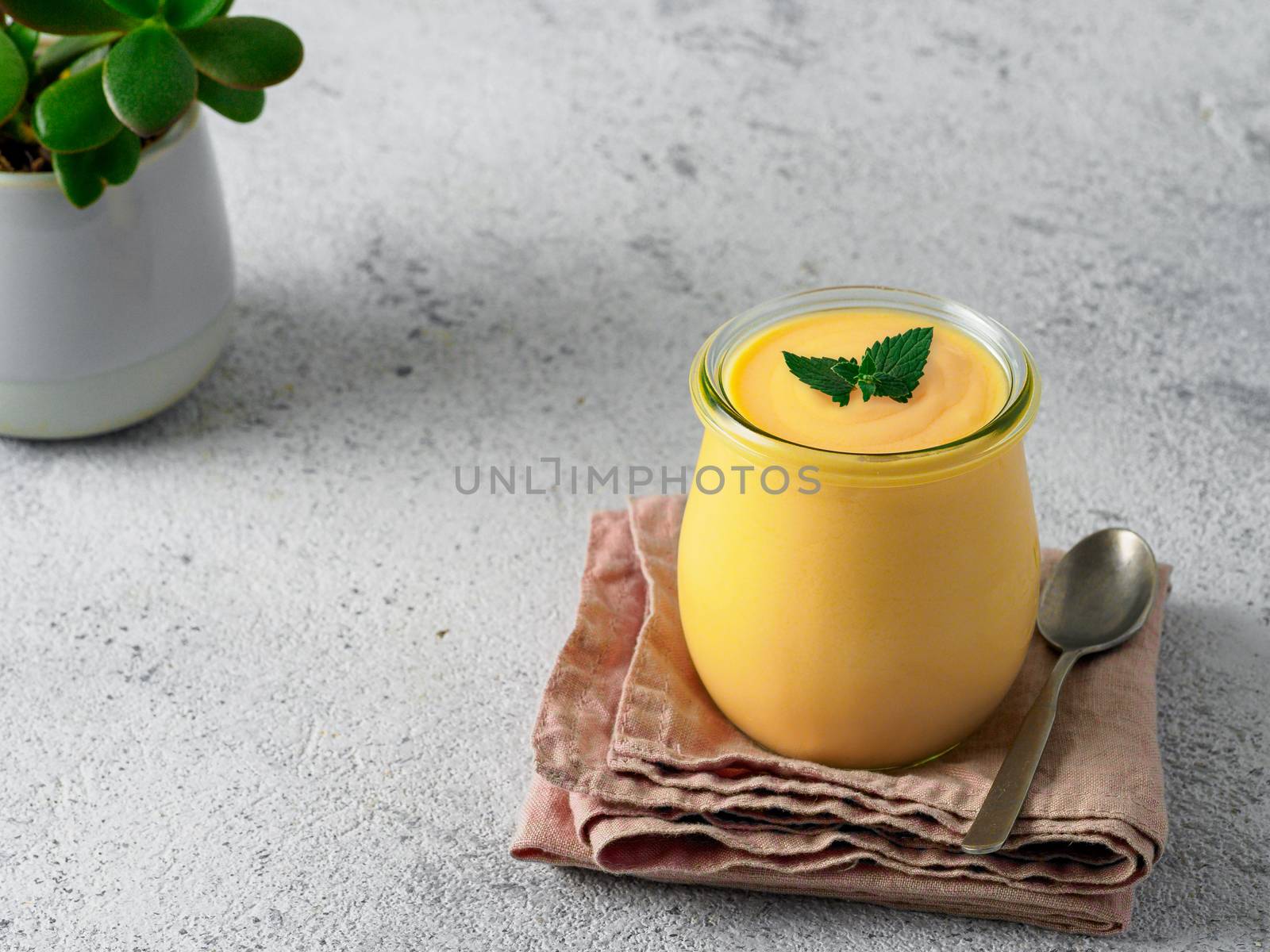 Yellow mango lassi on gray background. Indian mango yogurt drink with copy space left.