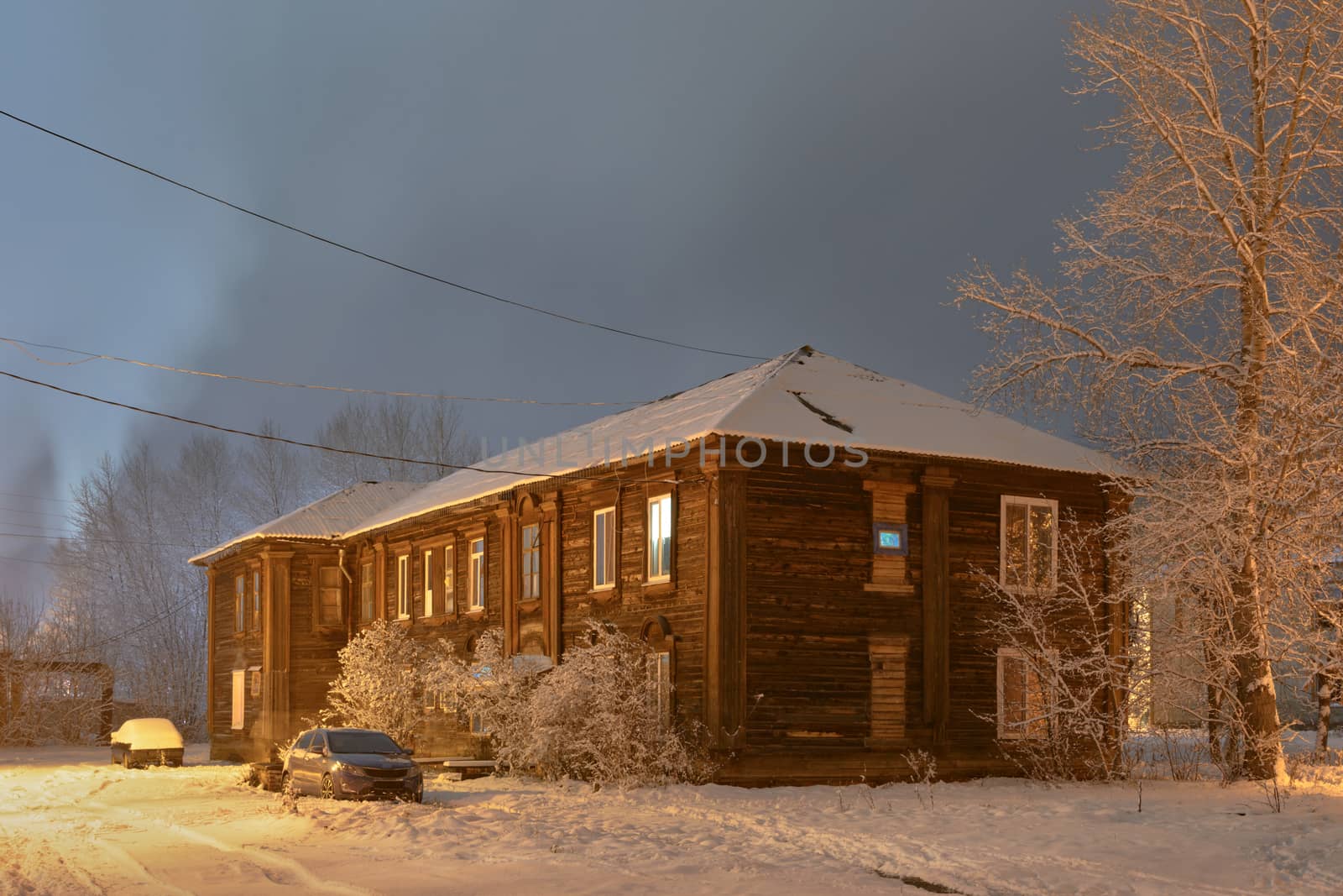 Winter street in night illumination with an old house in the foreground