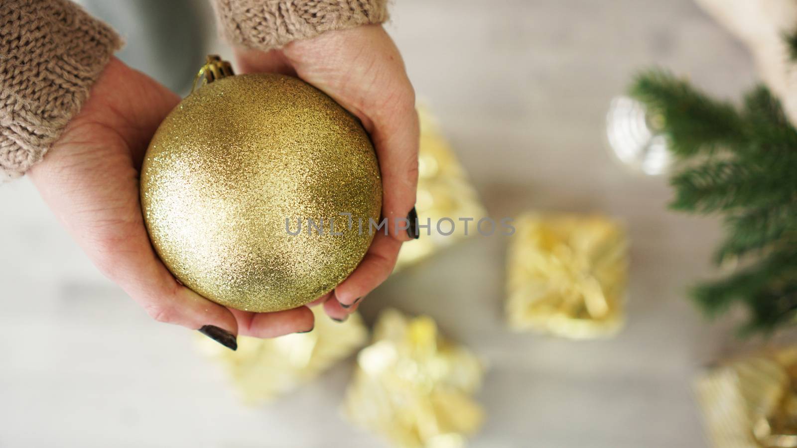 Hand holding gold ball decorations on Christmas tree background by natali_brill