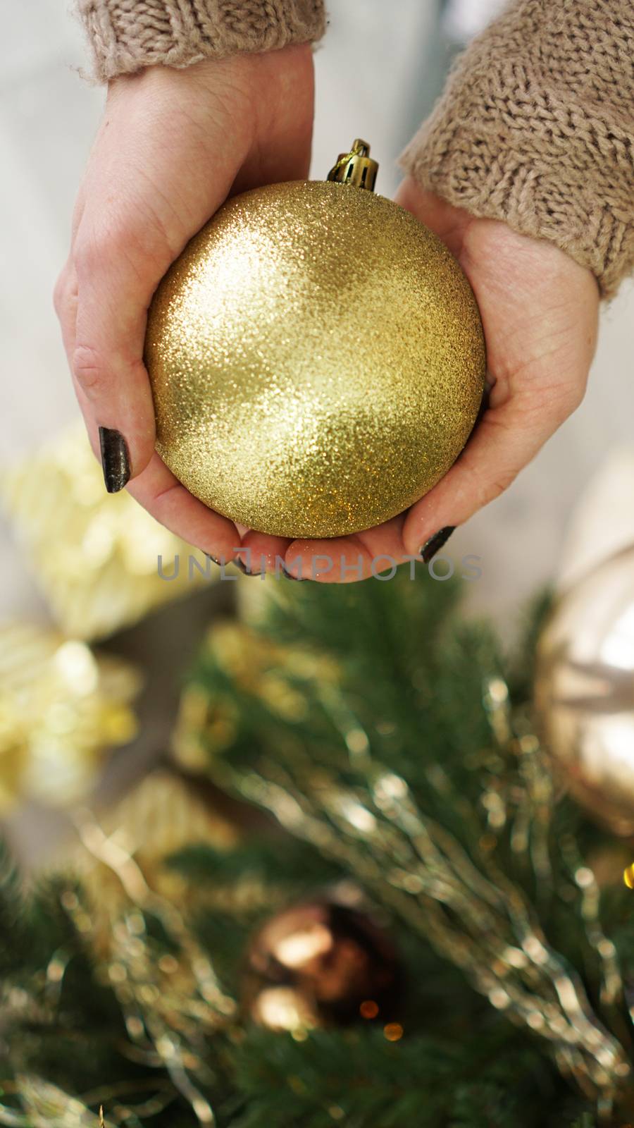 Hand holding gold ball decorations on Christmas tree background by natali_brill