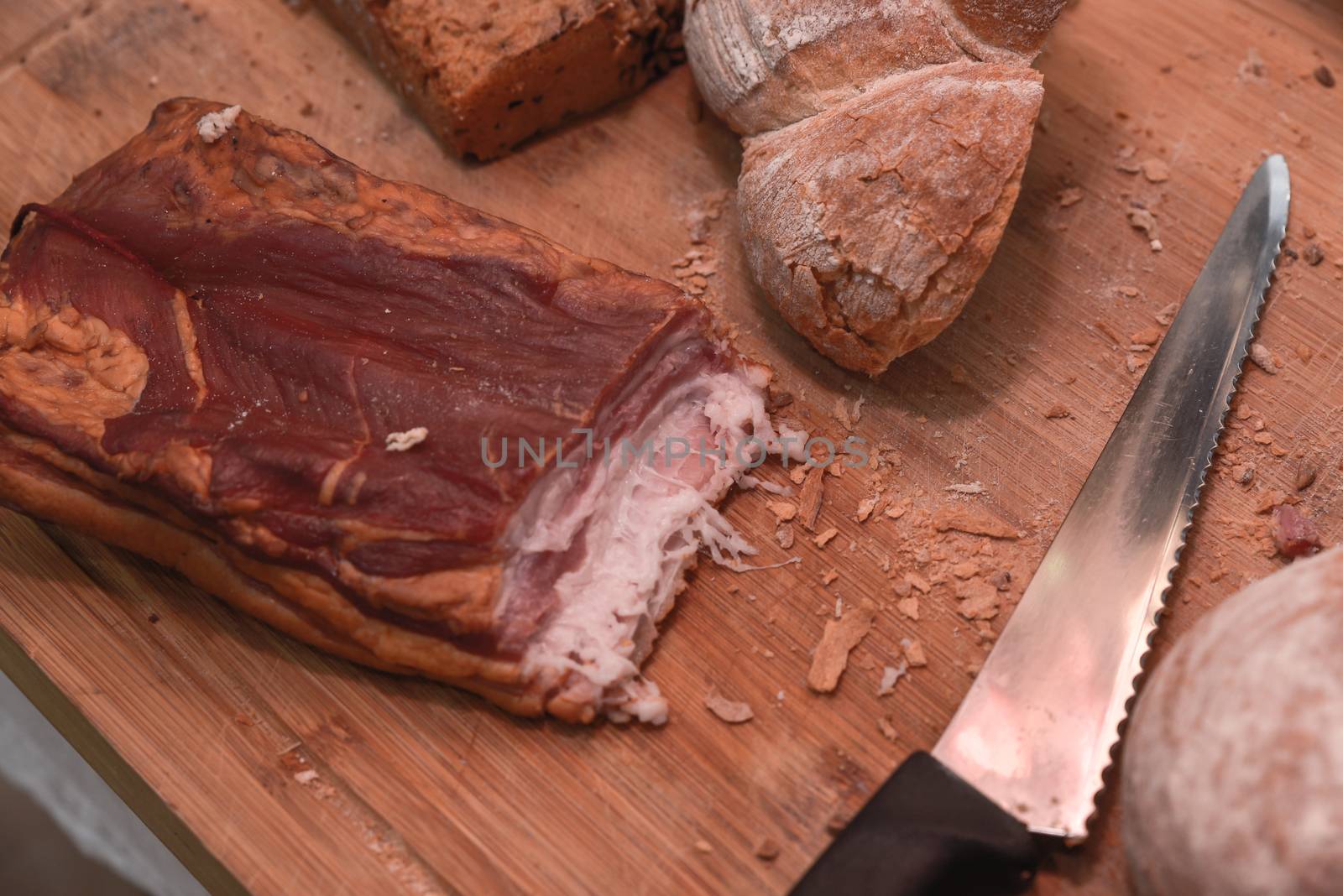 Smoked bacon with bread and knife on cutting board